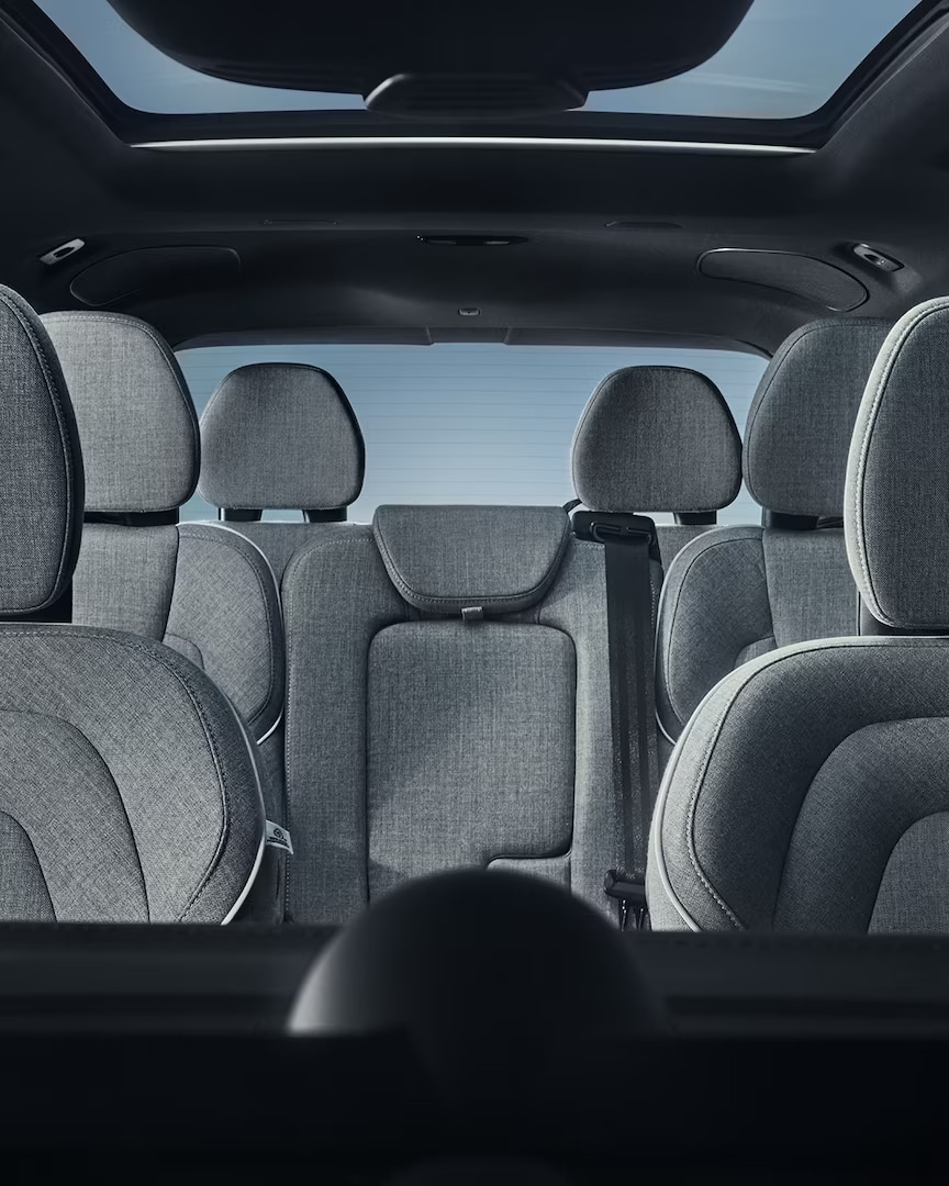 Širokoúhlý pohled na sedm sedadel čalouněných vlněným materiálem v interiéru plug-in hybridního vozu Volvo XC90.