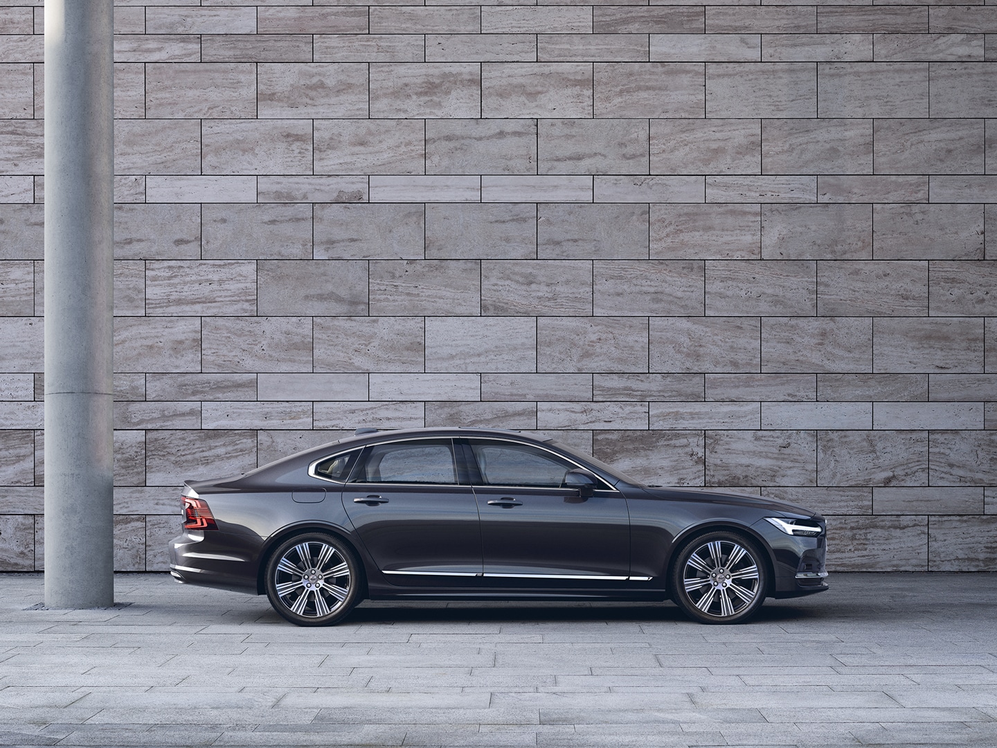 Volvo S90 sedd från sidan parkerad framför en grå betongvägg.