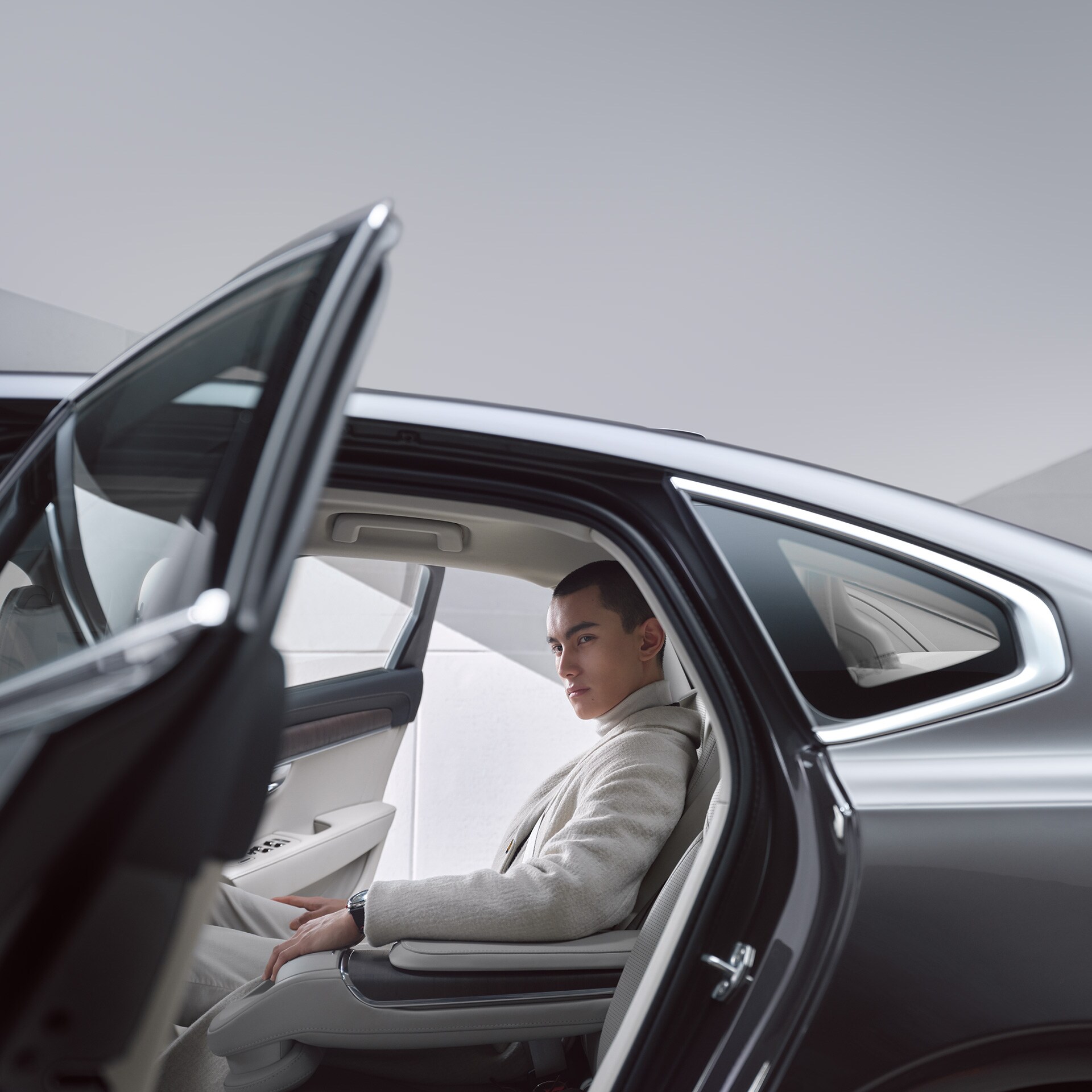 A man sitting in the back seat of a Volvo S90.
