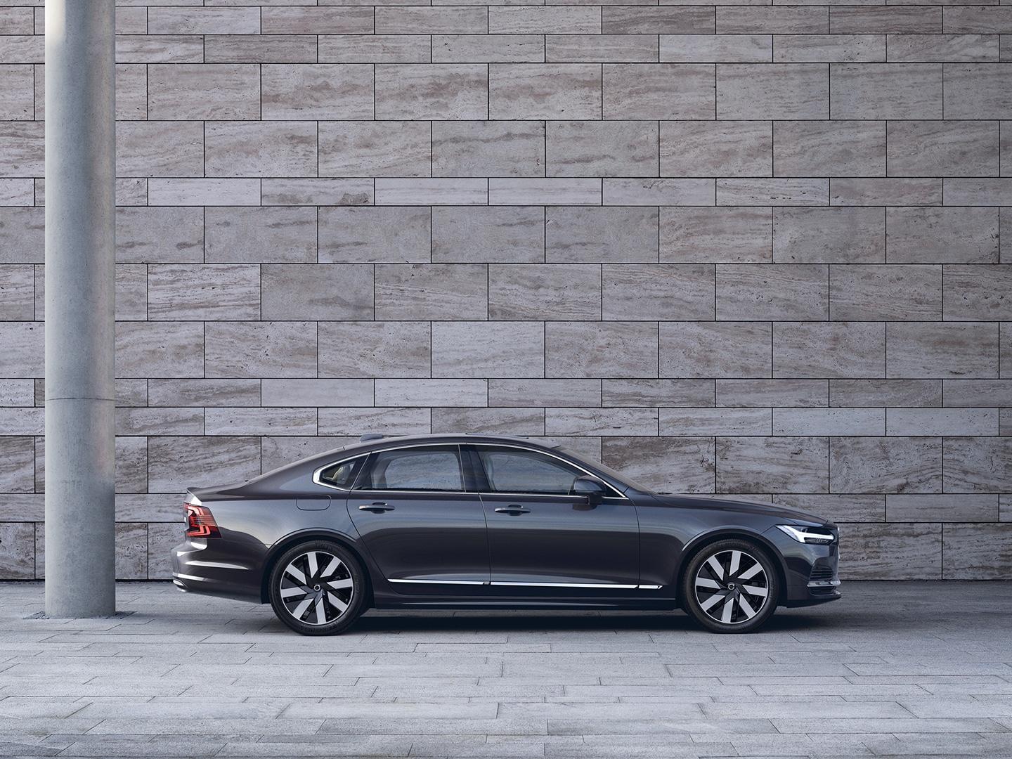 A Volvo S90 Recharge is parked in front of a set of stairs.