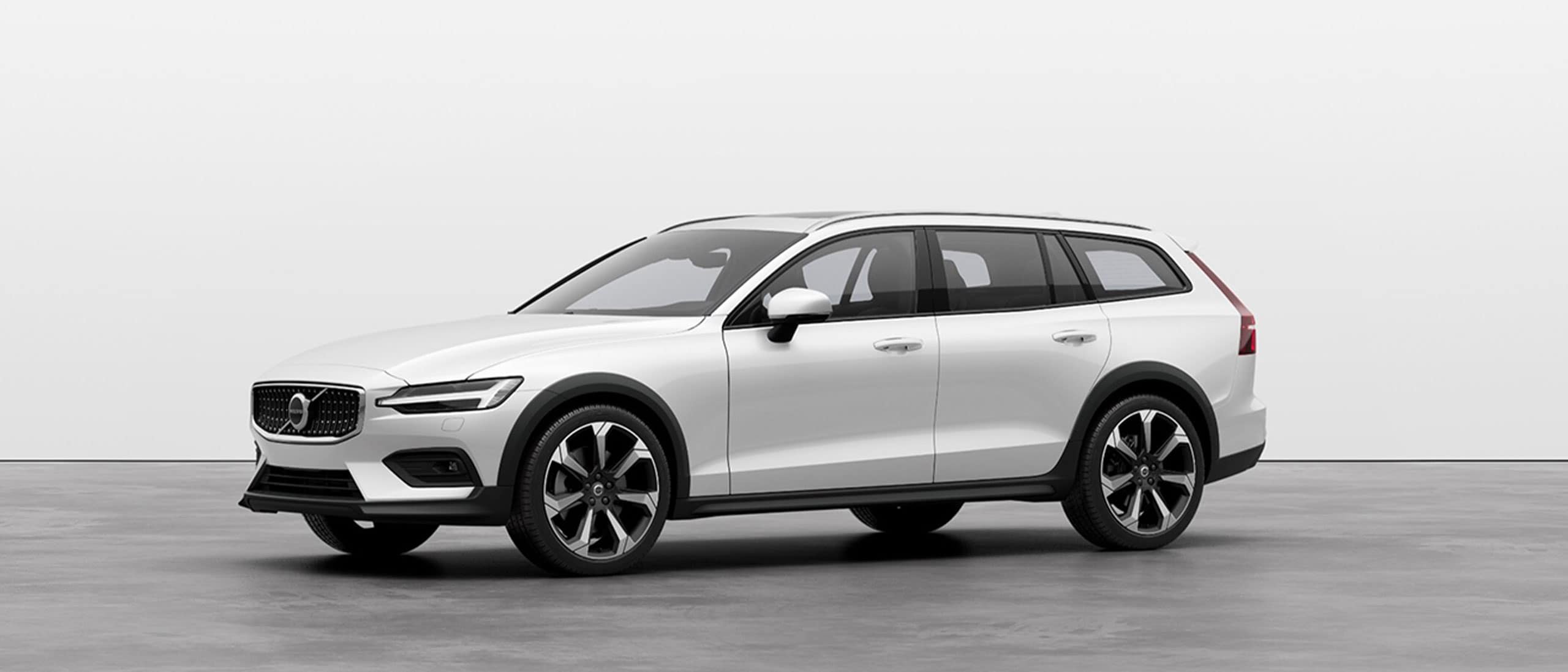 A white Volvo V60 Cross Country standing still on grey floor in a studio.
