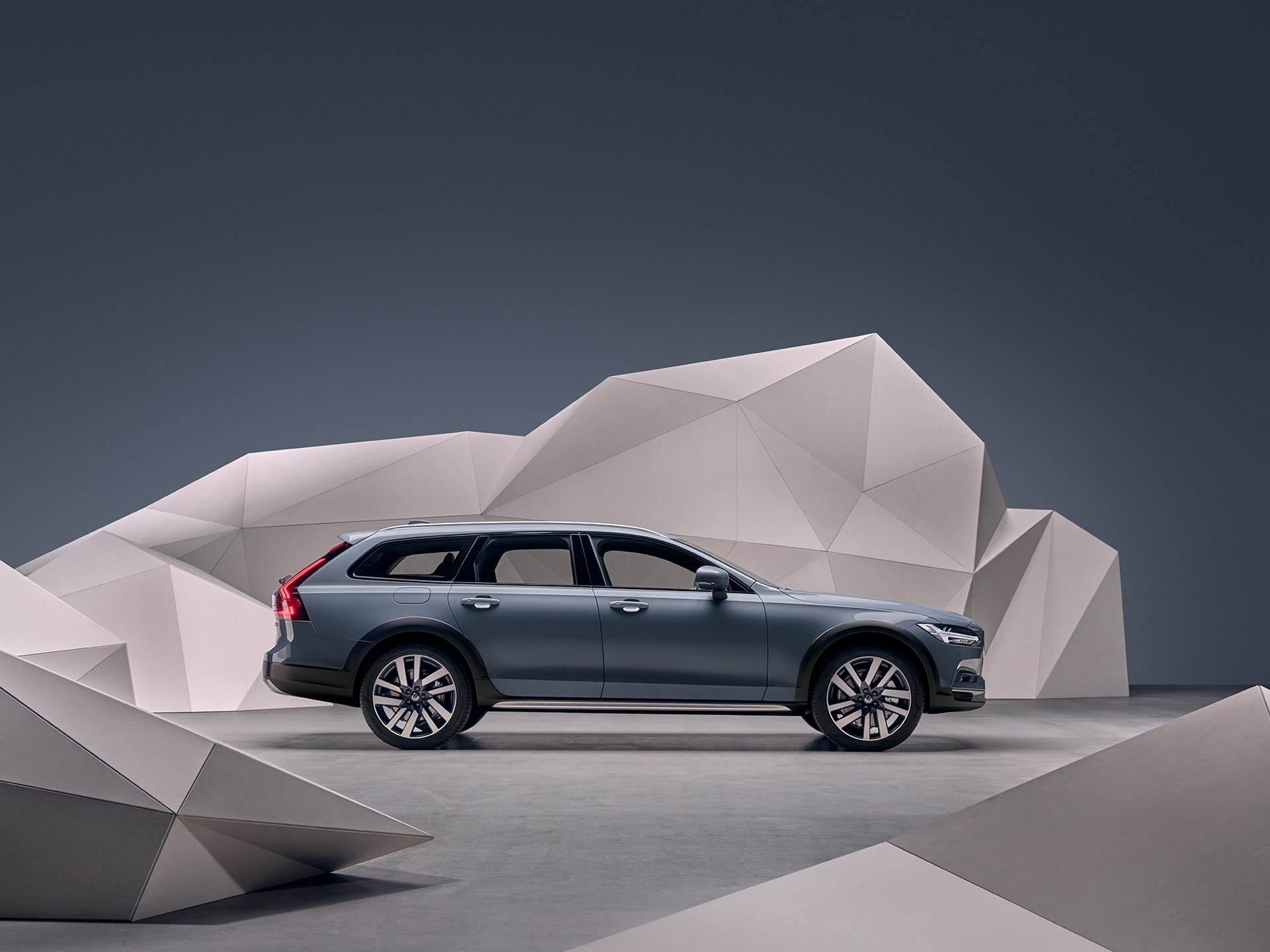 A grey Volvo V90 Cross Country standing in front of an artistic wall.