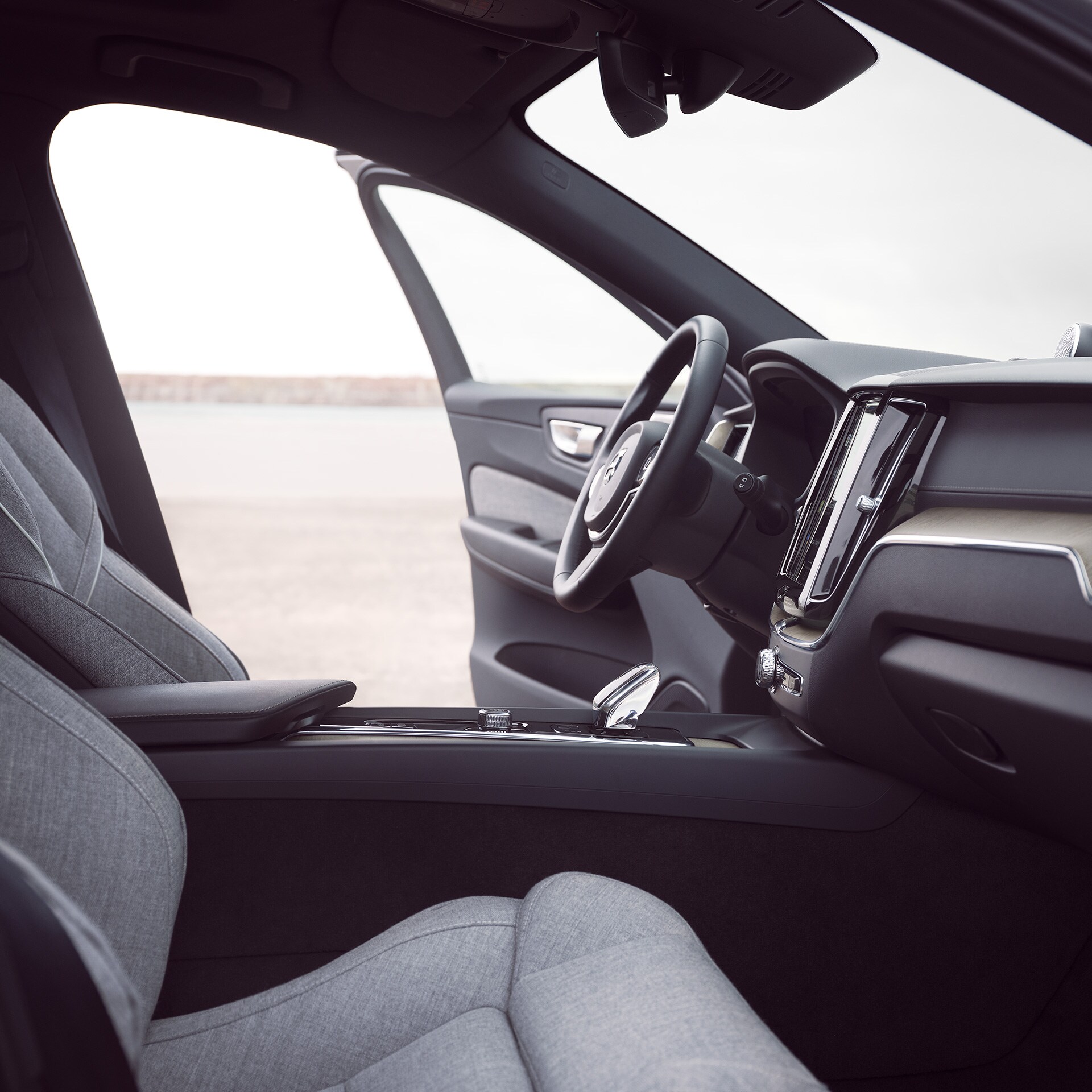 Sürücü qapısı açıq şəkildə Volvo XC60 Recharge avtomobilinin ön interyeri.