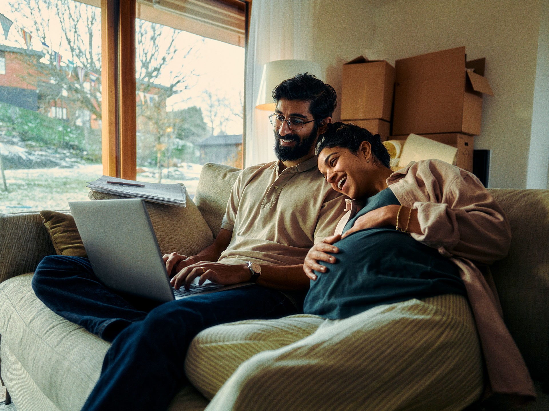 Una giovane coppia seduta davanti a un computer portatile calcola i possibili risparmi.