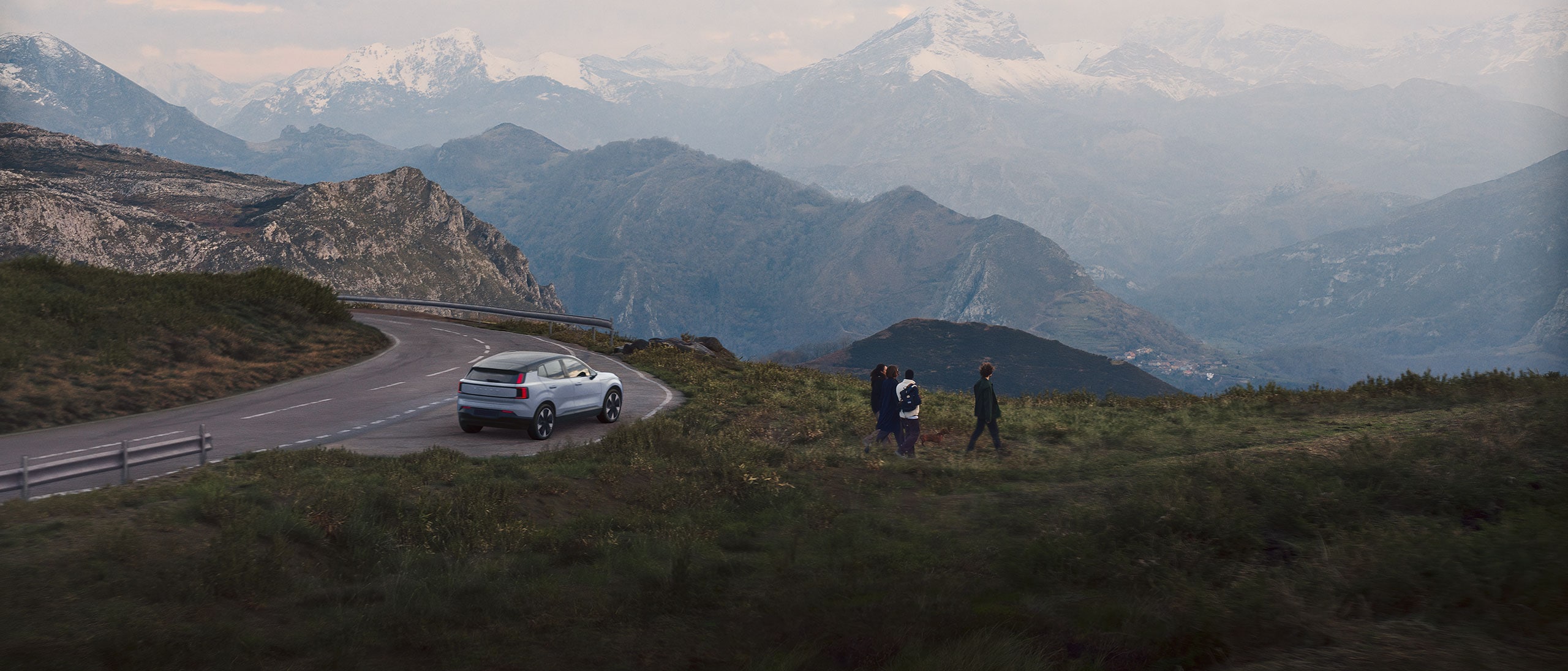 A fully electric Volvo car parked on the side of a beautiful mountainous landscape.