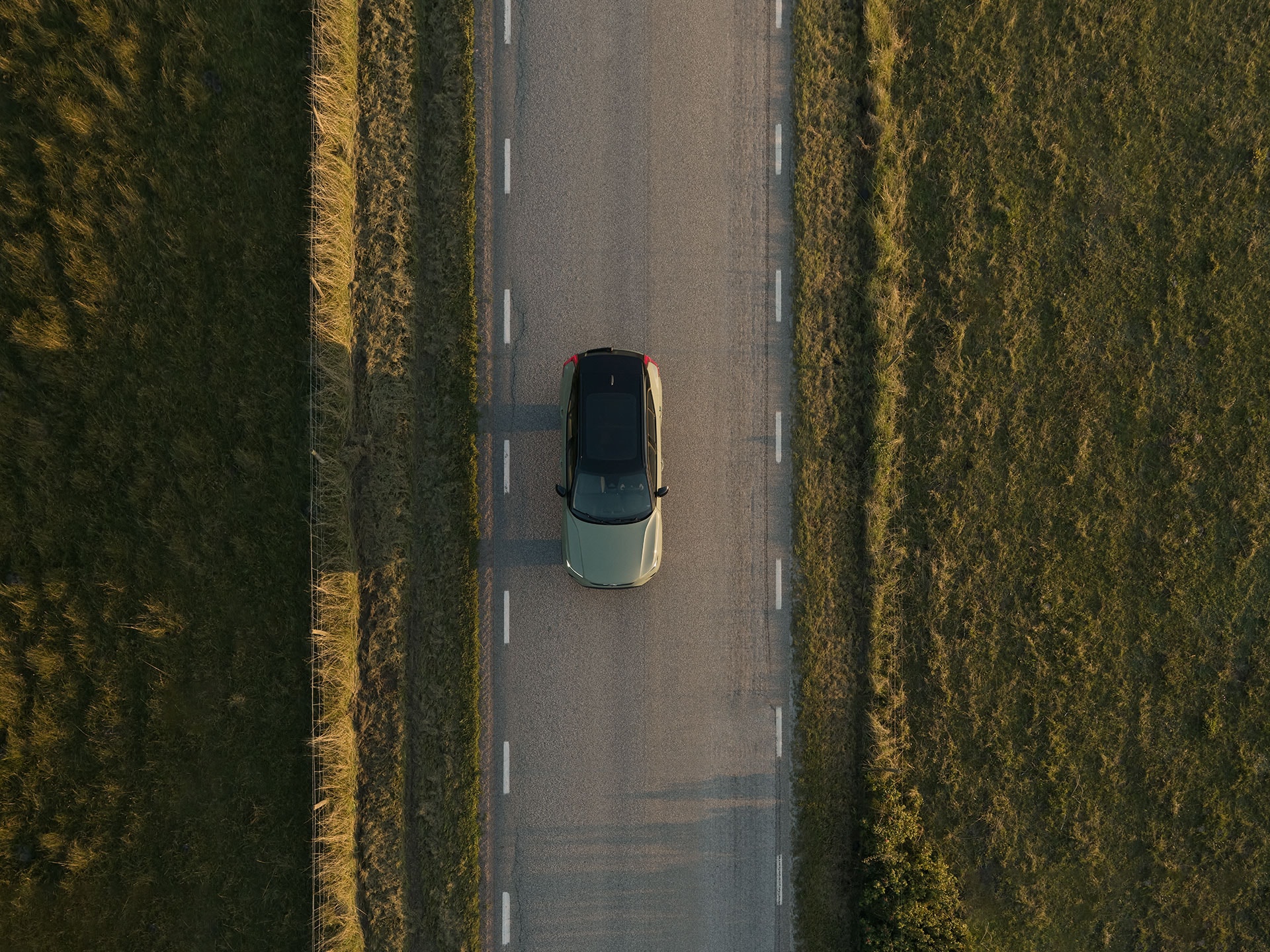 An electric Volvo car driving on a countryside road.