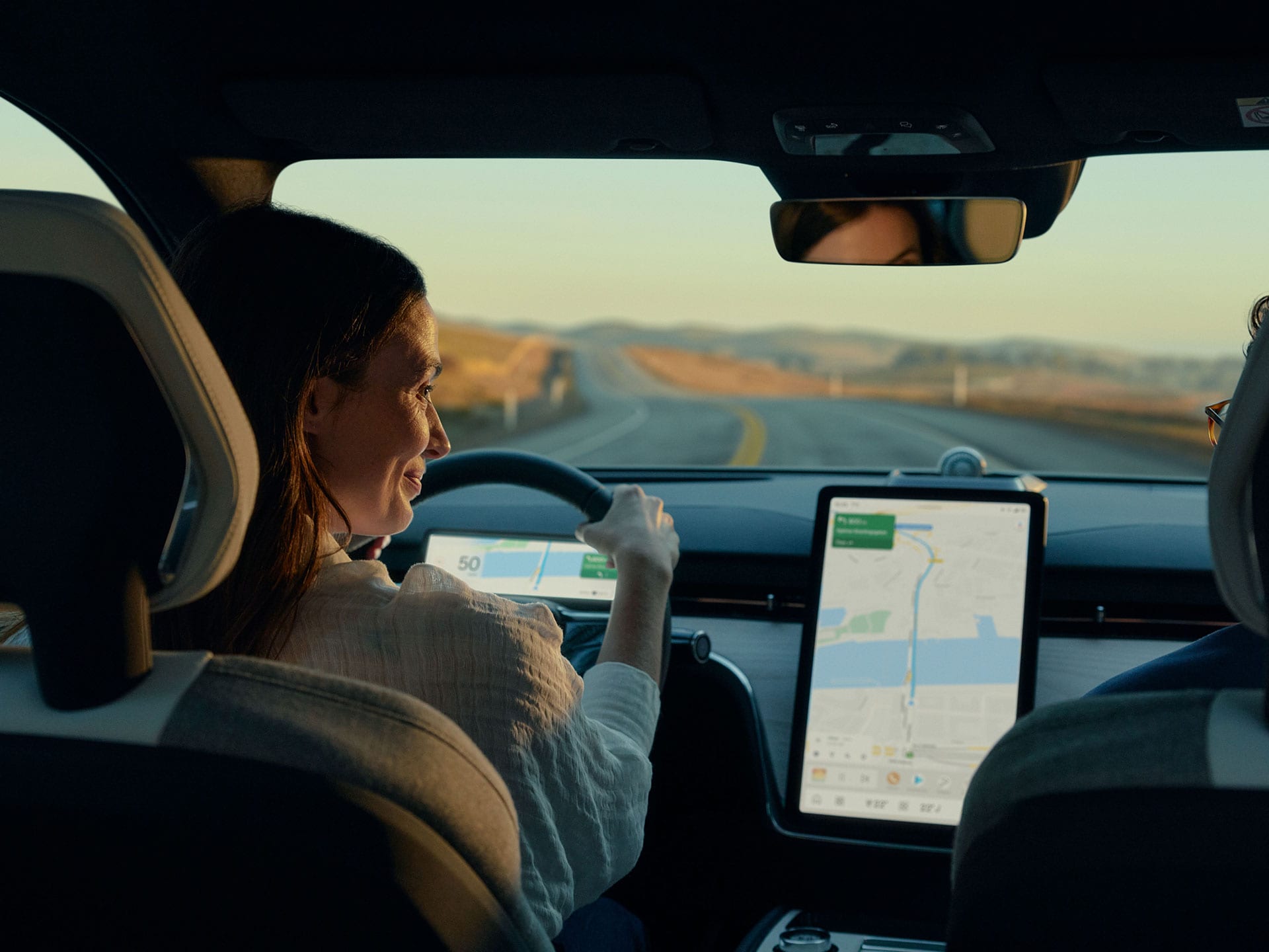 Image montrant une femme conduisant une Volvo EX90 tout en regardant son impressionnant écran central