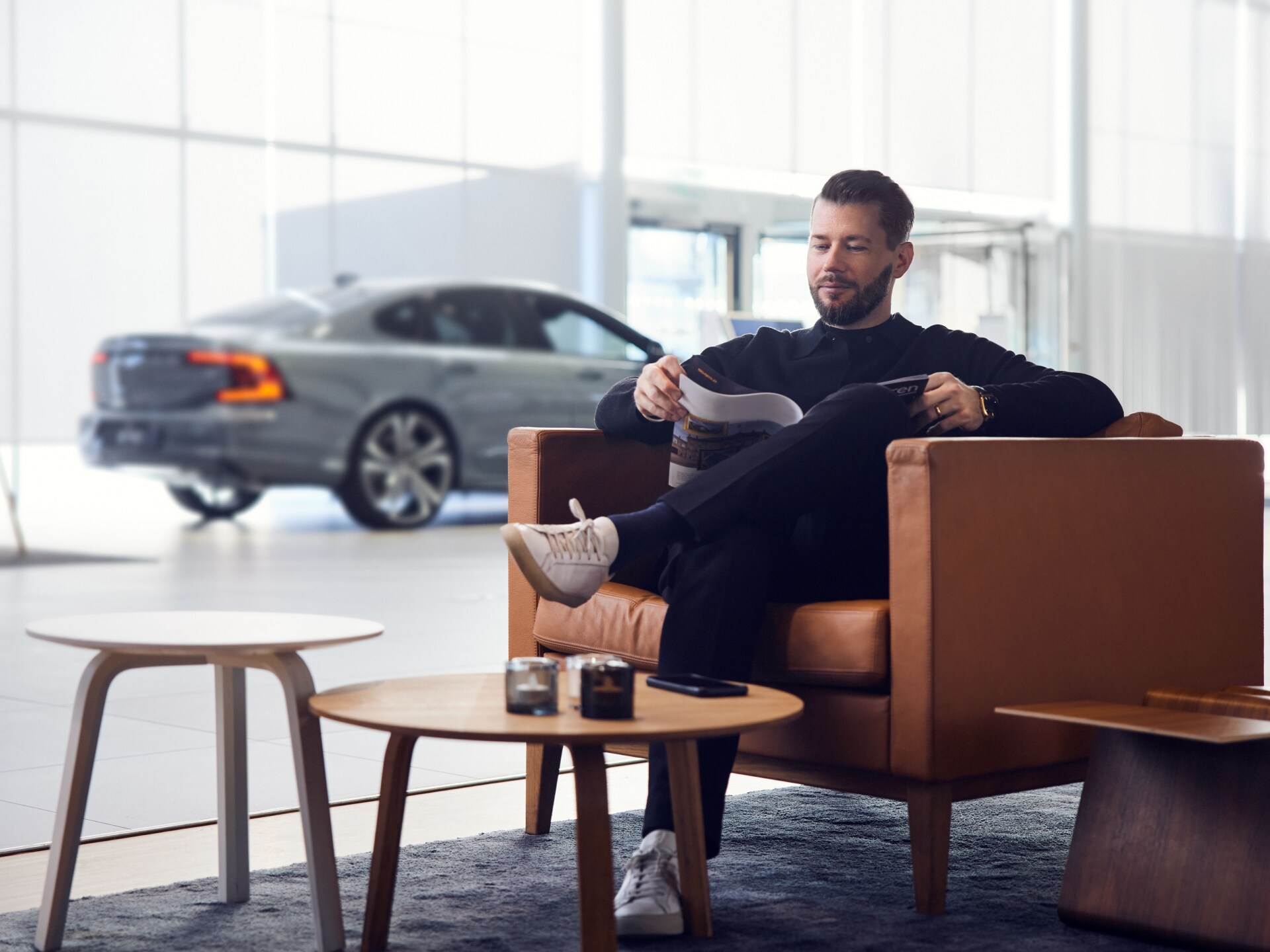 Un hombre sentado en el sofá de una sala de espera en un centro de servicio Volvo.