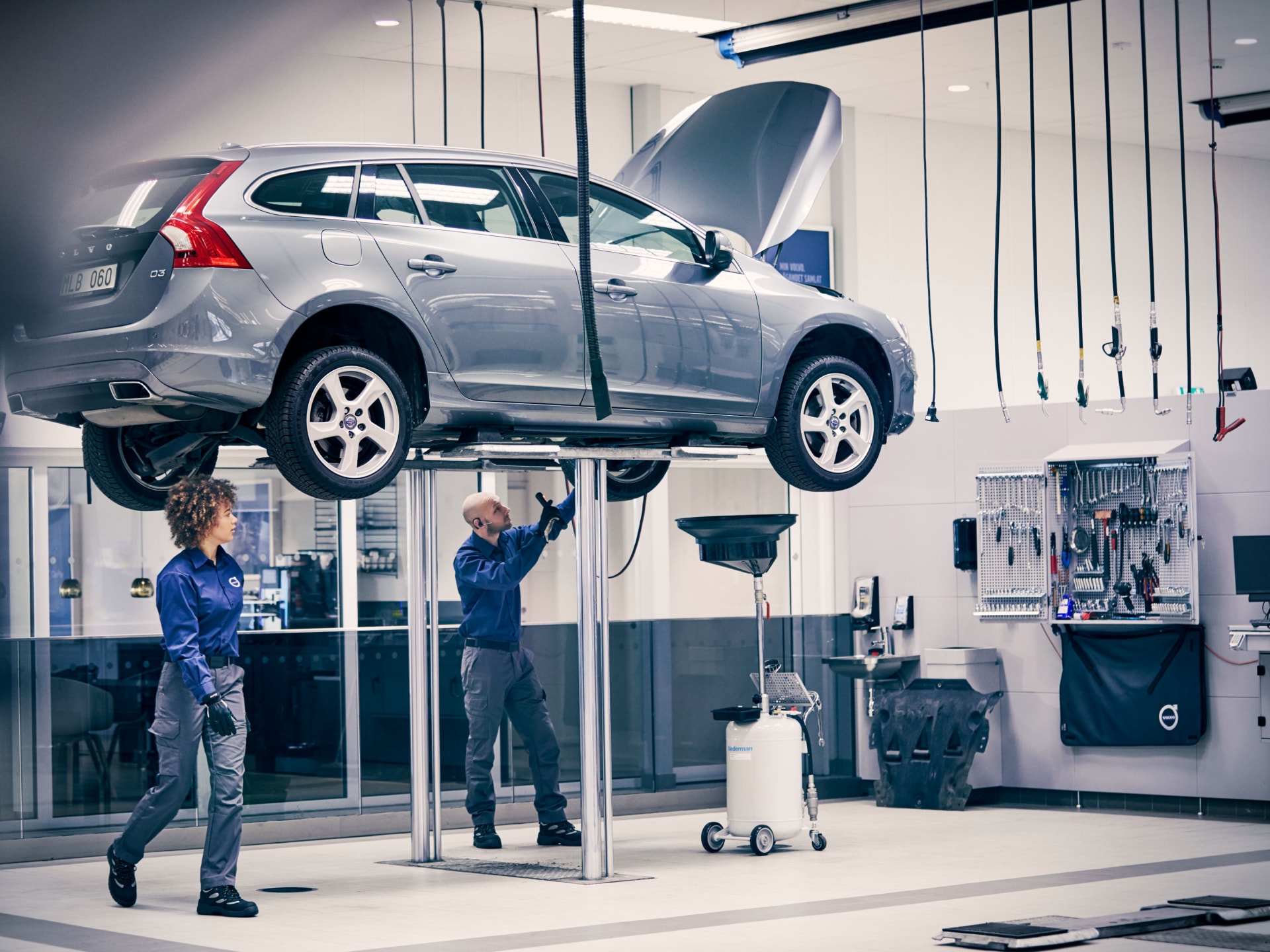 Dos técnicos de servicio Volvo dando mantenimiento a un Volvo XC60.