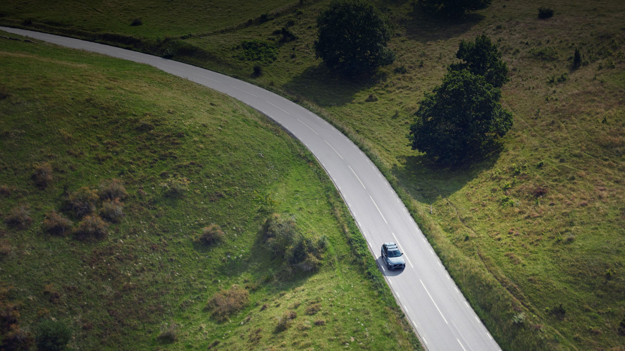 Volvo XC60 descendiendo una colina con prados verdes a los costados