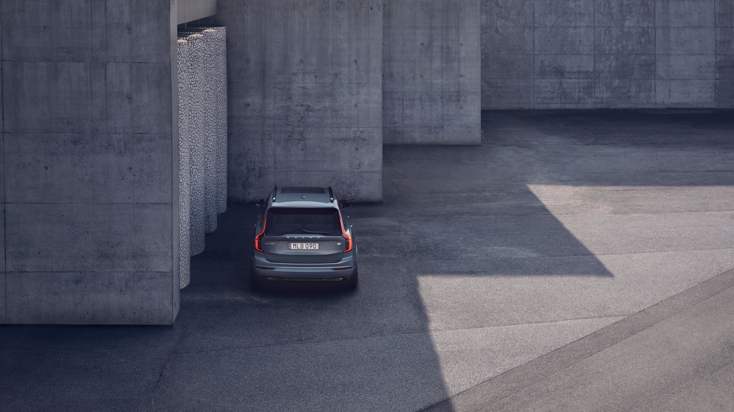 Ein grauer Volvo XC90 steht außen vor einer grauen Wand