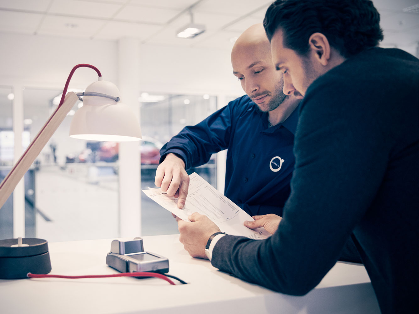 Persoonlijke servicetechnicus van Volvo bespreekt details met klant aan een bureau.