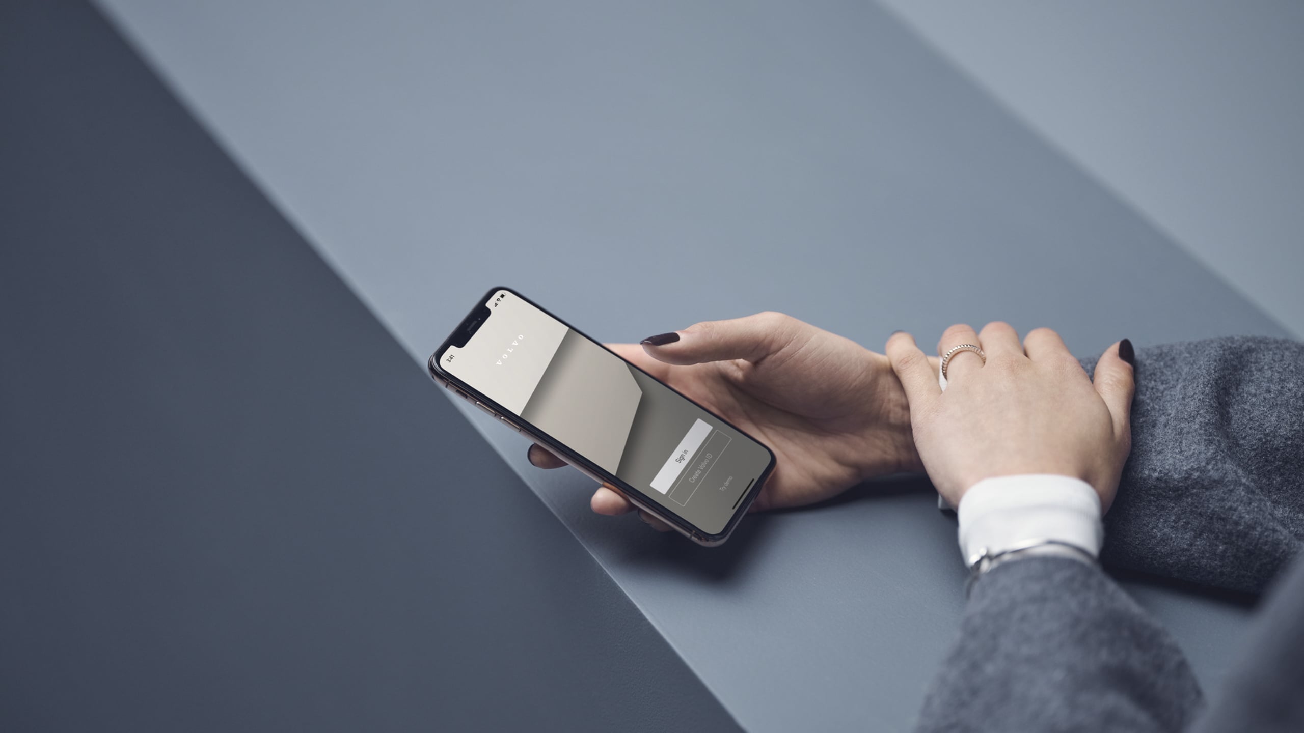 Una persona sosteniendo un teléfono celular sobre un fondo gris.