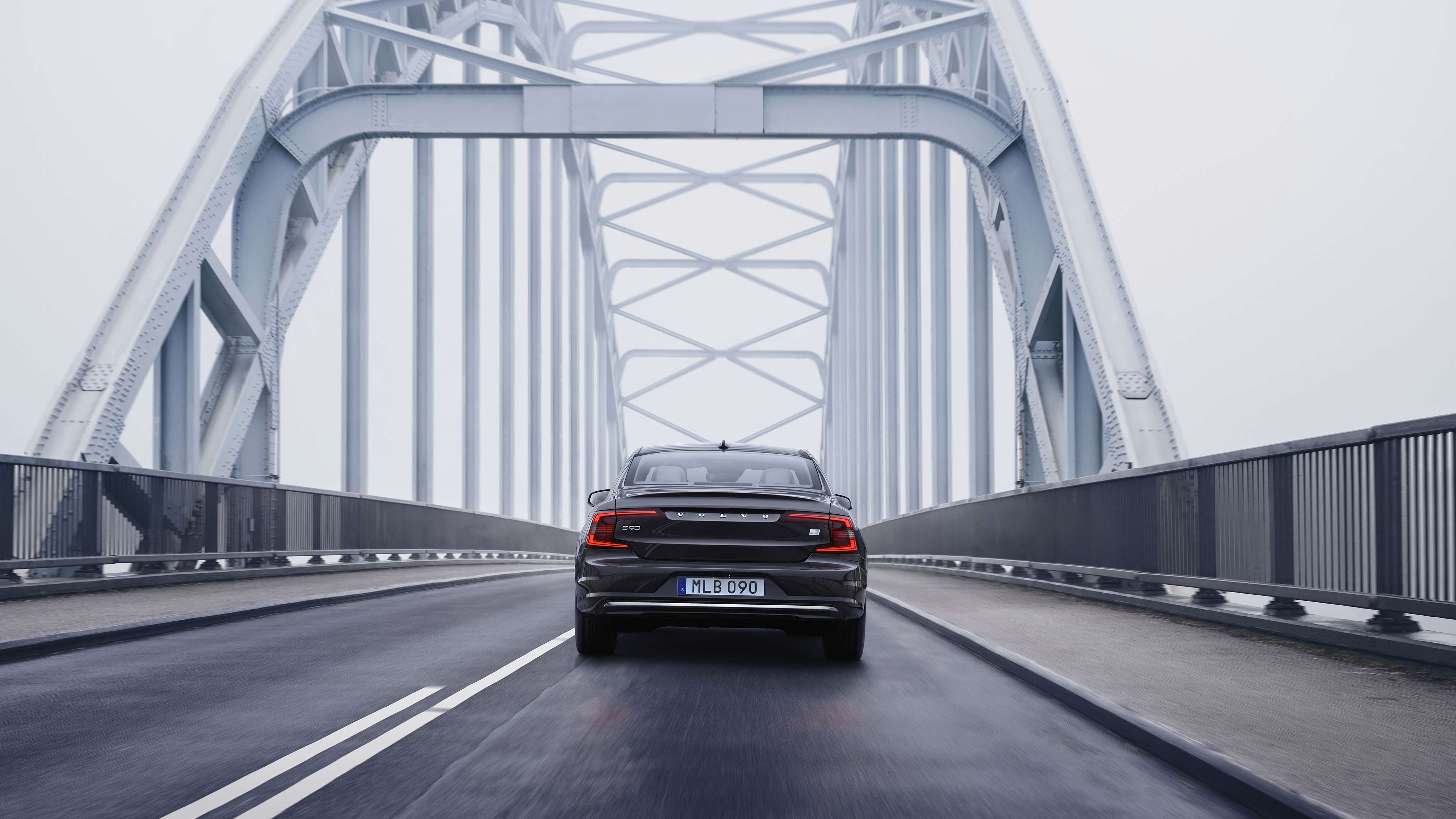 Takaapäin kuvattu musta Volvo S90 ylittämässä siltaa.
