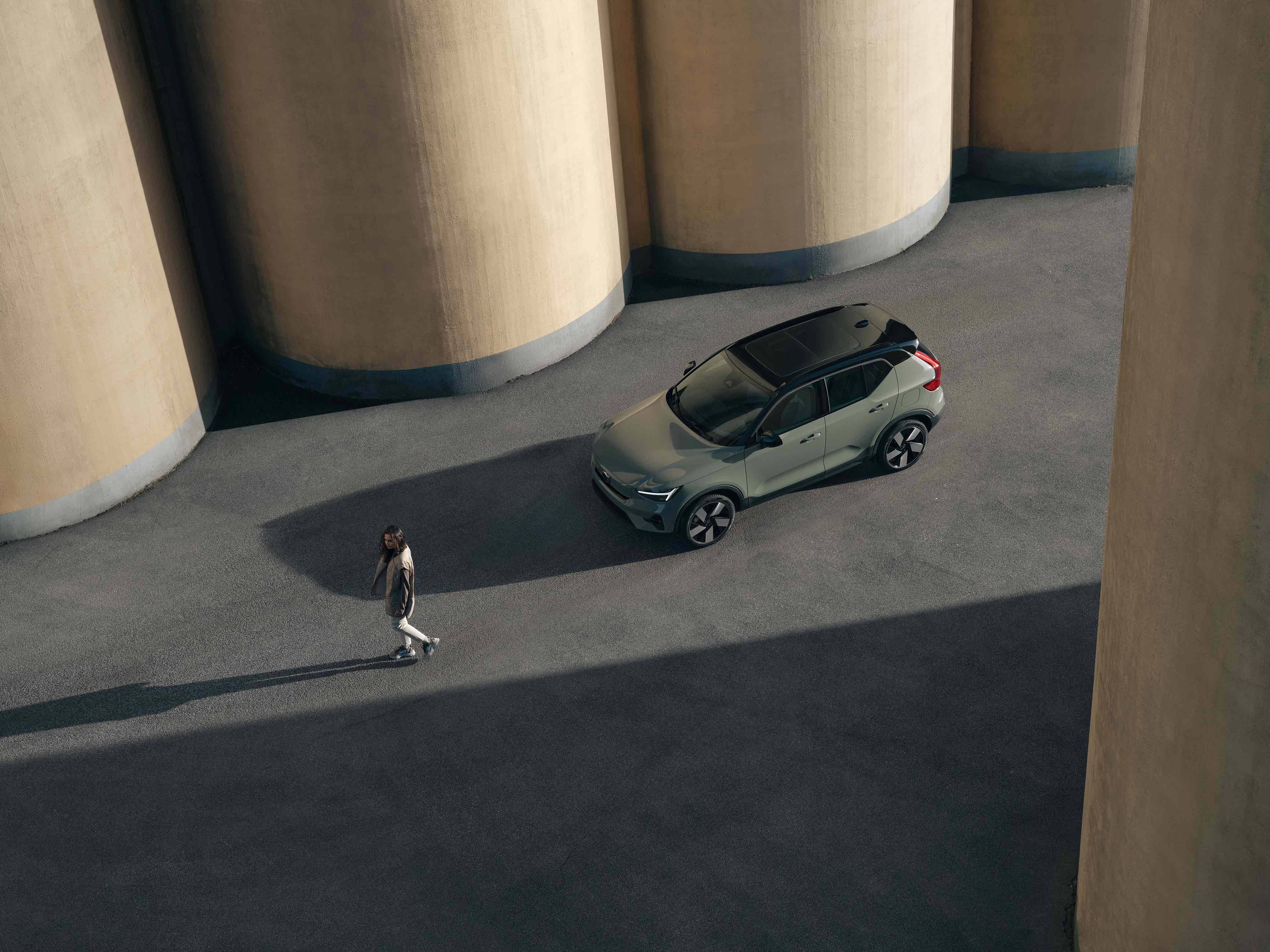 Birdseye view of a woman and a Sage Green Volvo XC40FL Recharge 