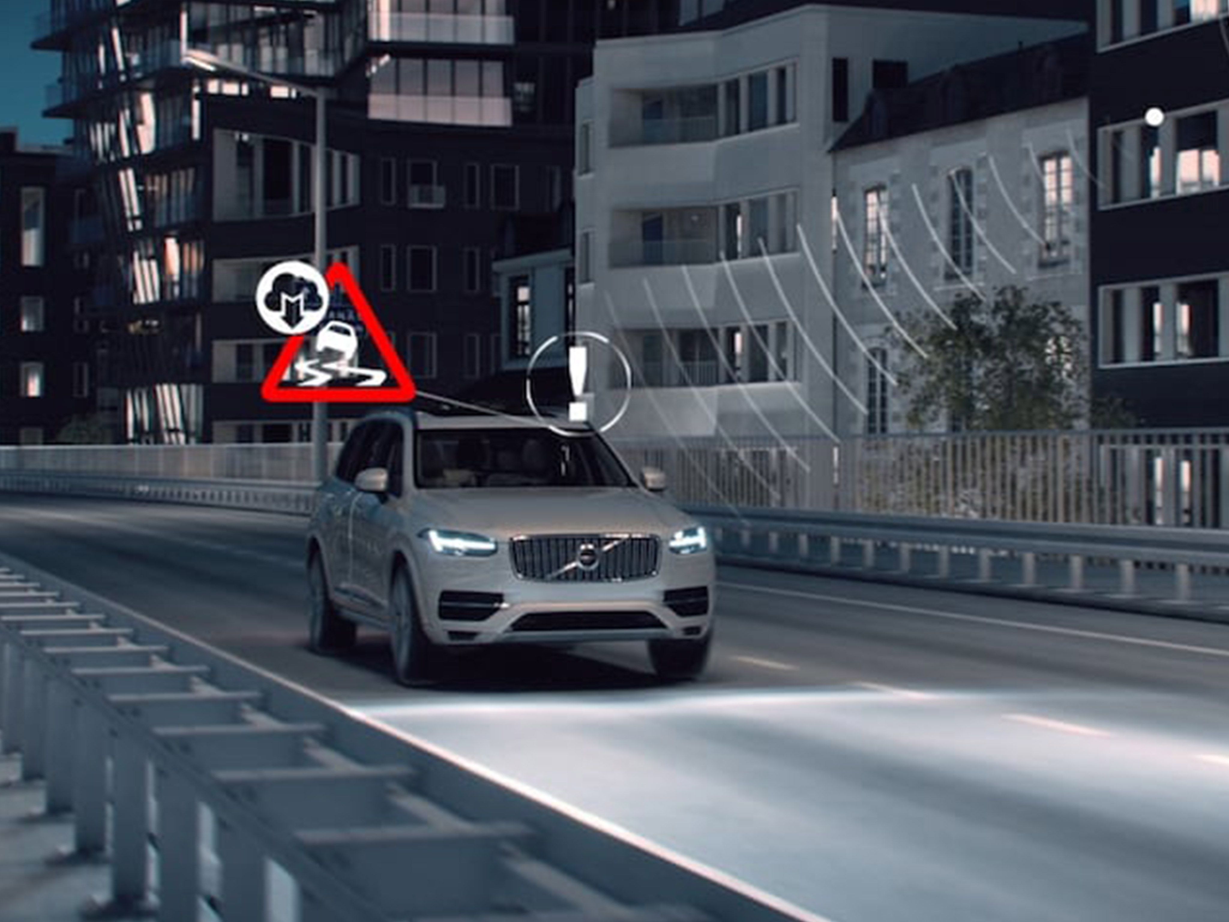 Valkoinen Volvo ajaa öisessä katumaisemassa. Kuvaan on liitetty kuljettajalle kojetaululla näkyviä ajo-olosuhteisiin liittyviä varoitusvaloja.