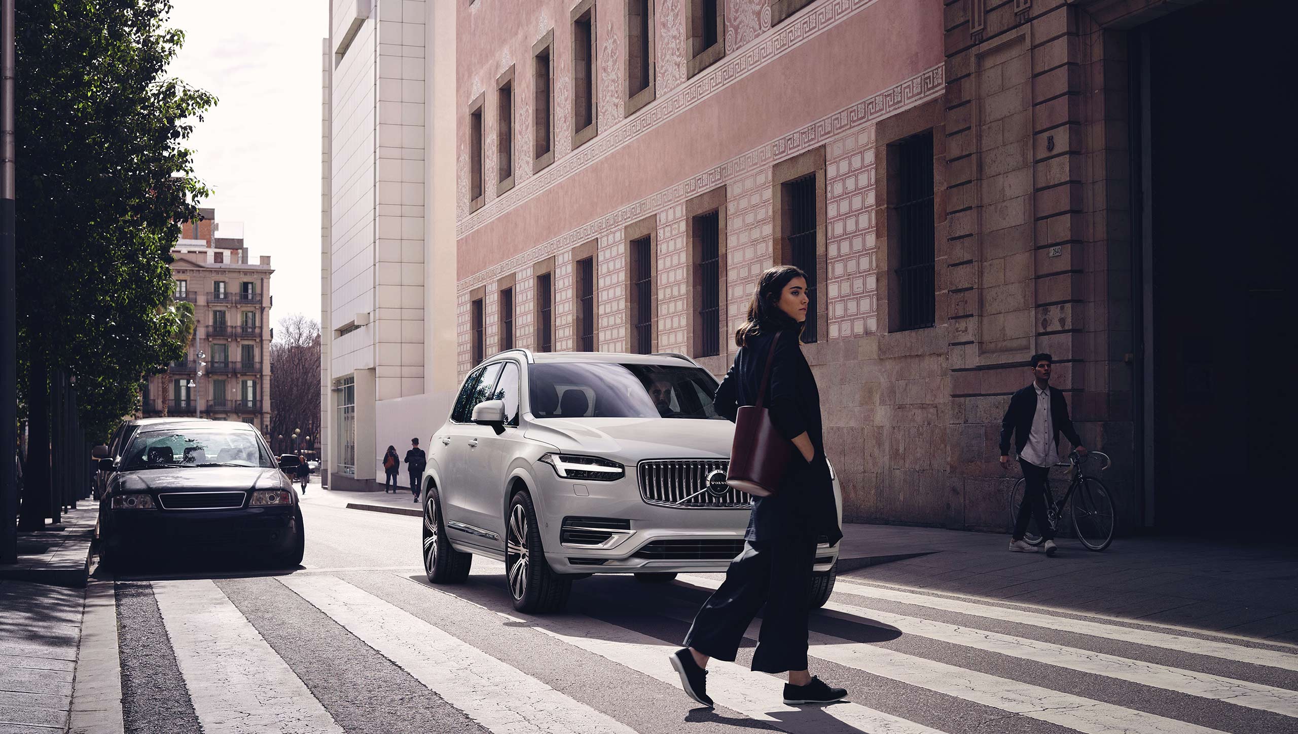 Bright Light Metallic Volvo XC90 stopped to wait for a woman crossing a street.