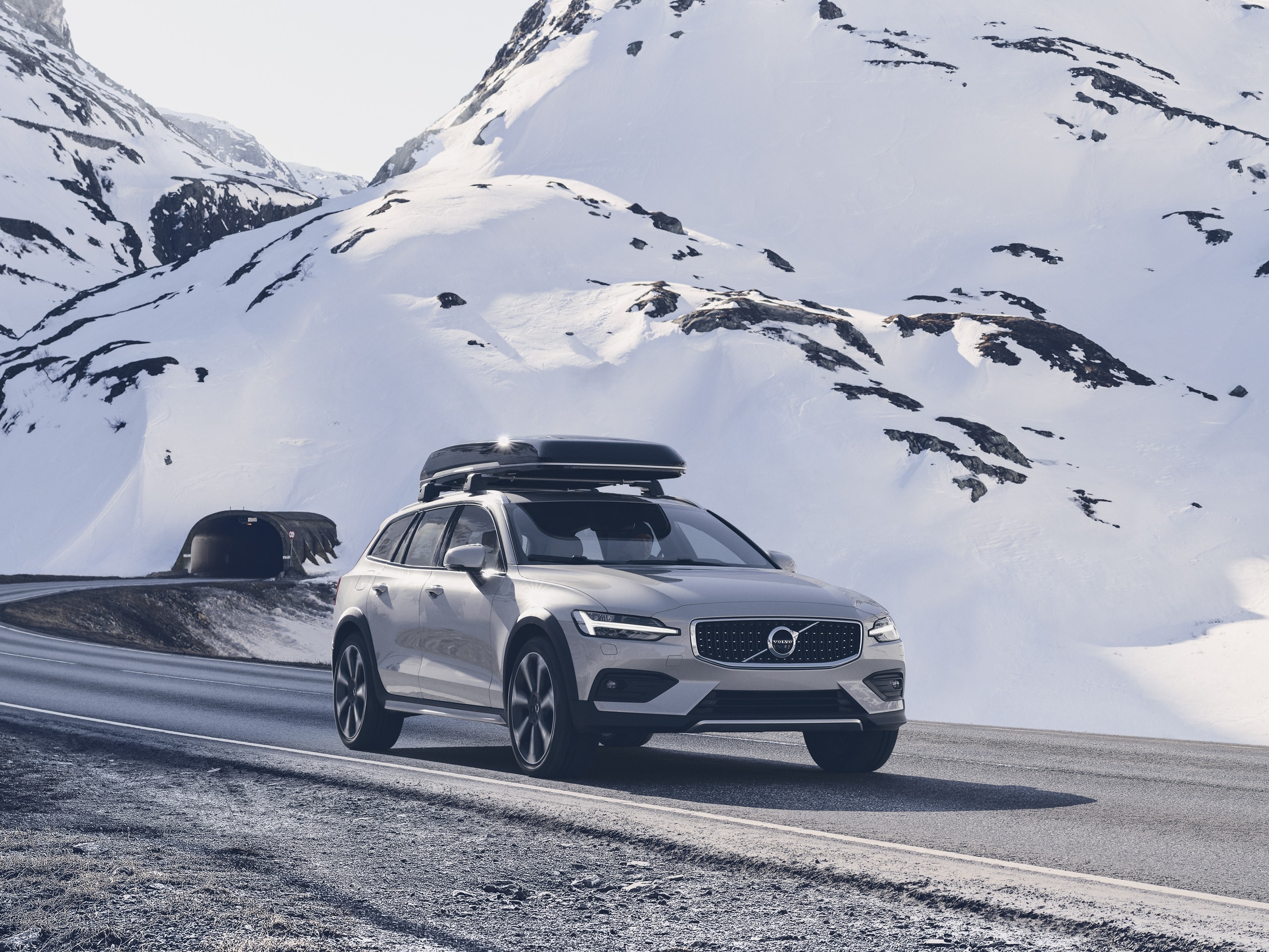Volvo V60 Cross Country avec coffre de toit sur une route de montagne enneigée