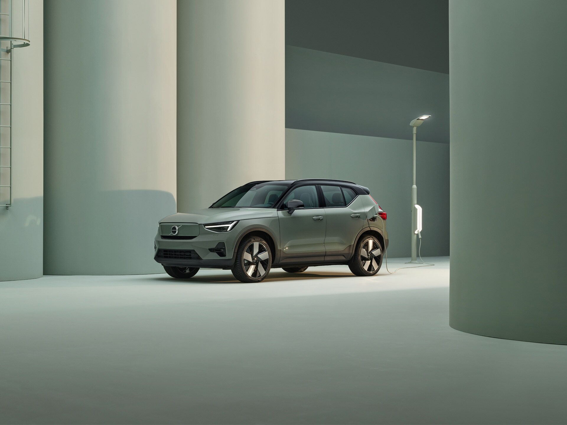 A glacier silver Volvo XC40 Recharge electric SUV charged in a pink city.