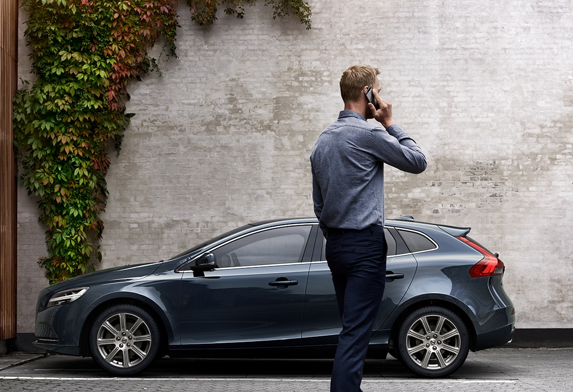 Homme au téléphone devant une voiture Volvo de profil