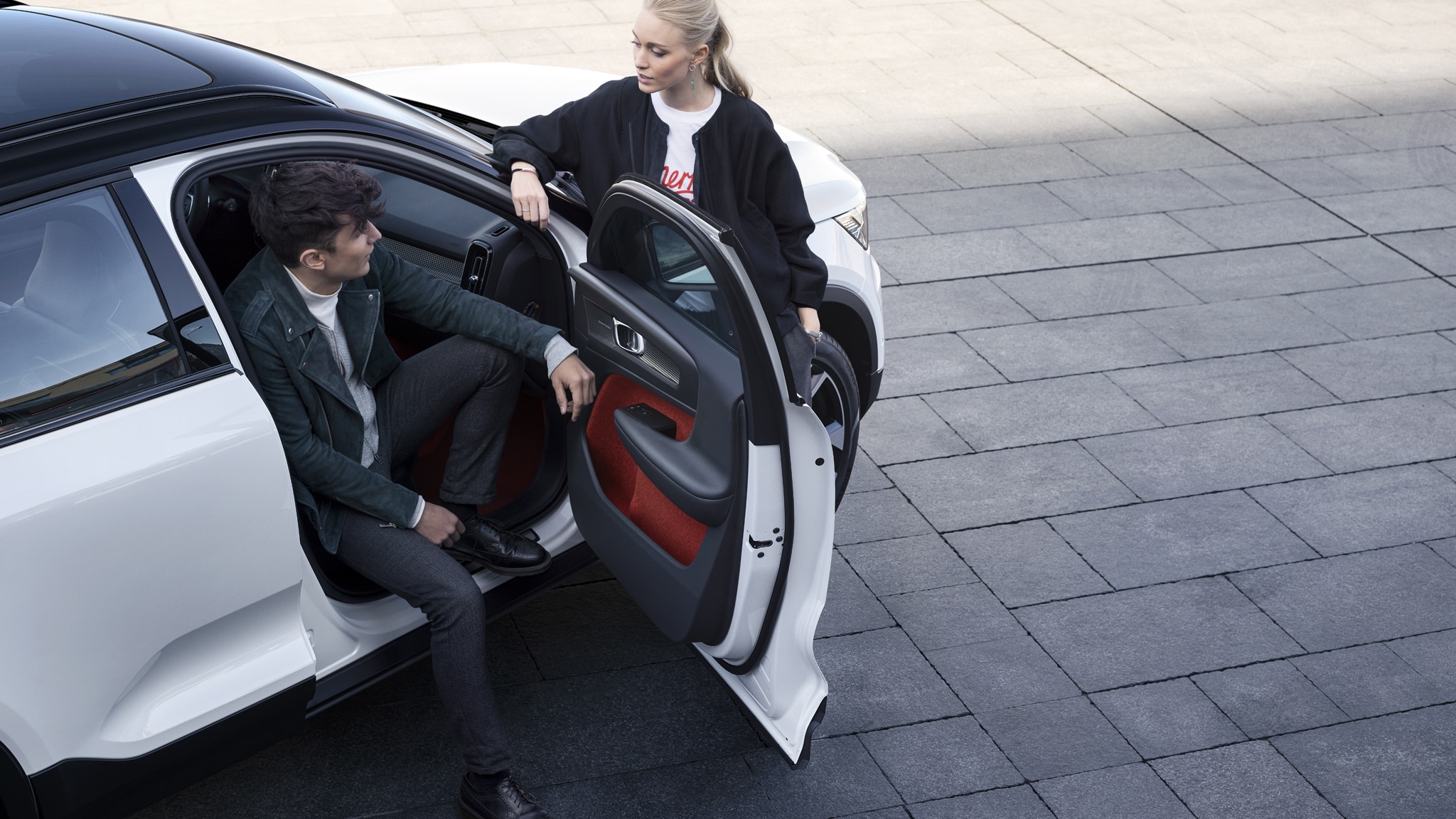 Homme et femme discutant à coté d'une voiture Volvo