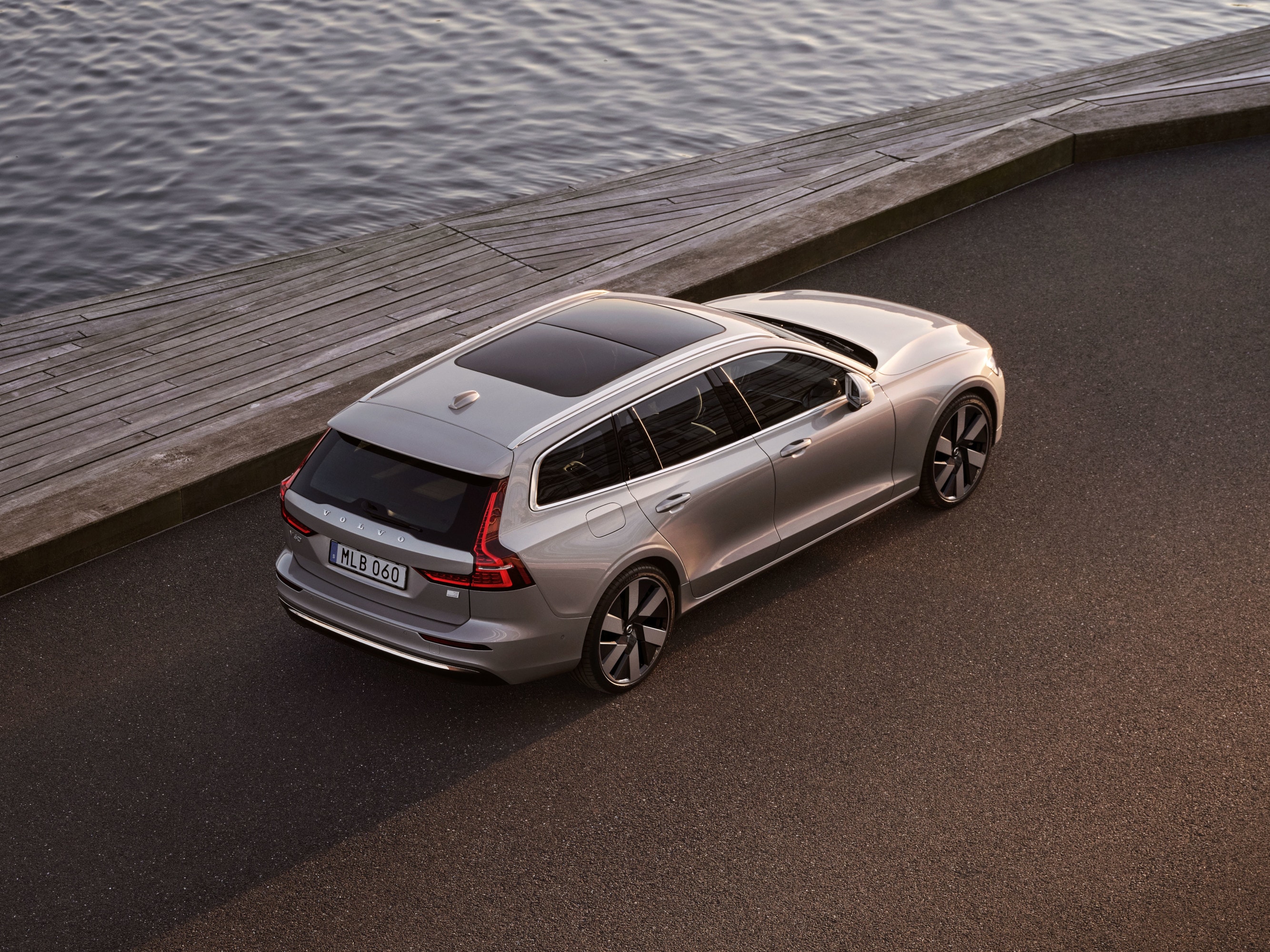 Sechs Volvo Fahrzeuge in der Farbe Crystal White Pearl stehen bei Sonnenuntergang aufgereiht auf einem Parkdeck