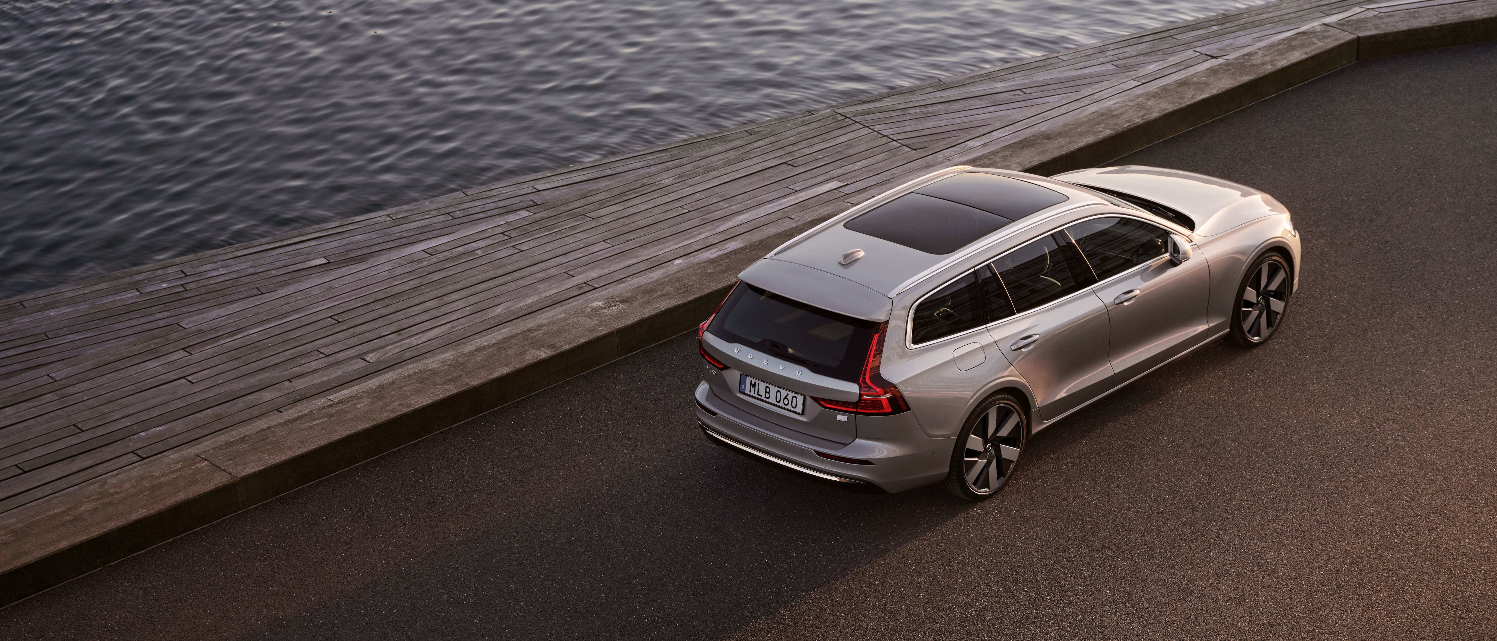 Sechs Volvo Fahrzeuge in der Farbe Crystal White Pearl stehen bei Sonnenuntergang aufgereiht auf einem Parkdeck