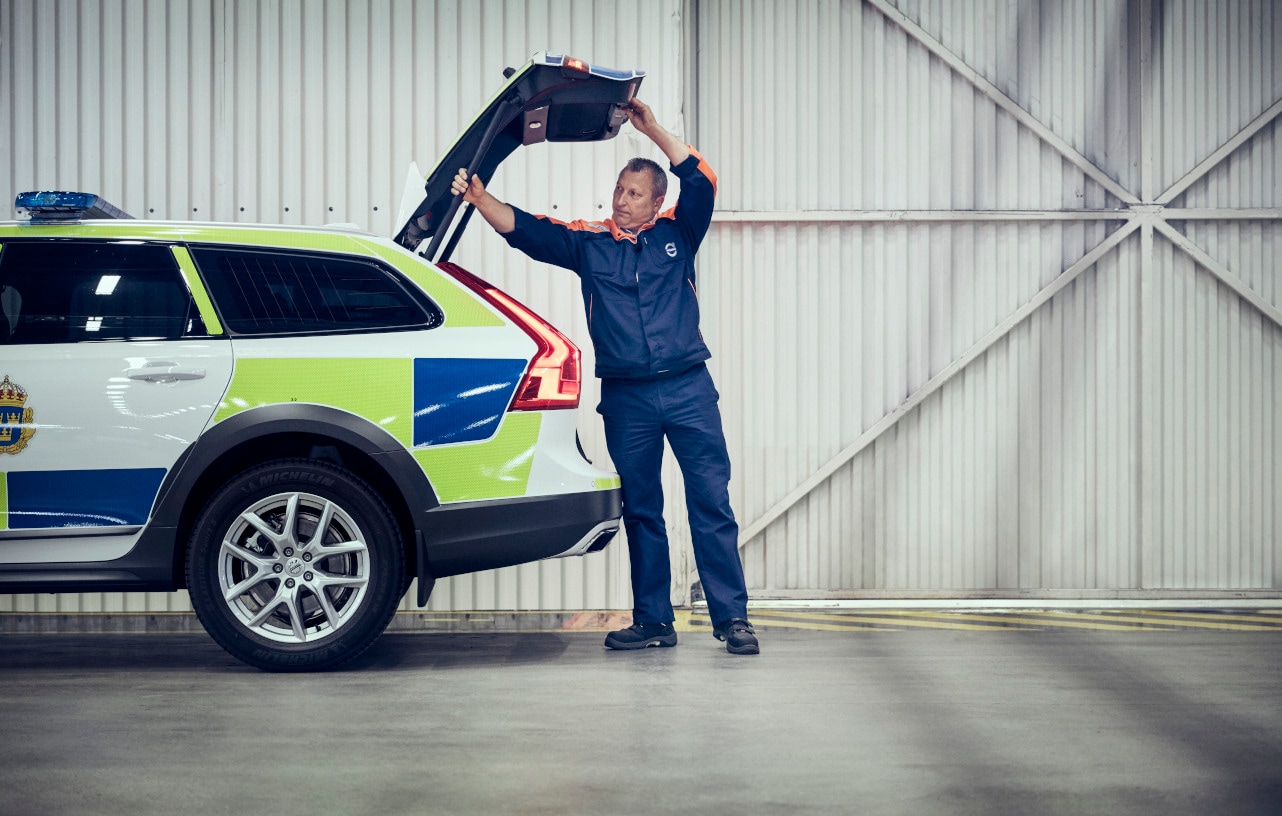 Ein Volvo Mitarbeiter arbeitet am geöffneten Kofferraum eines Volvo Polizeifahrzeugs
