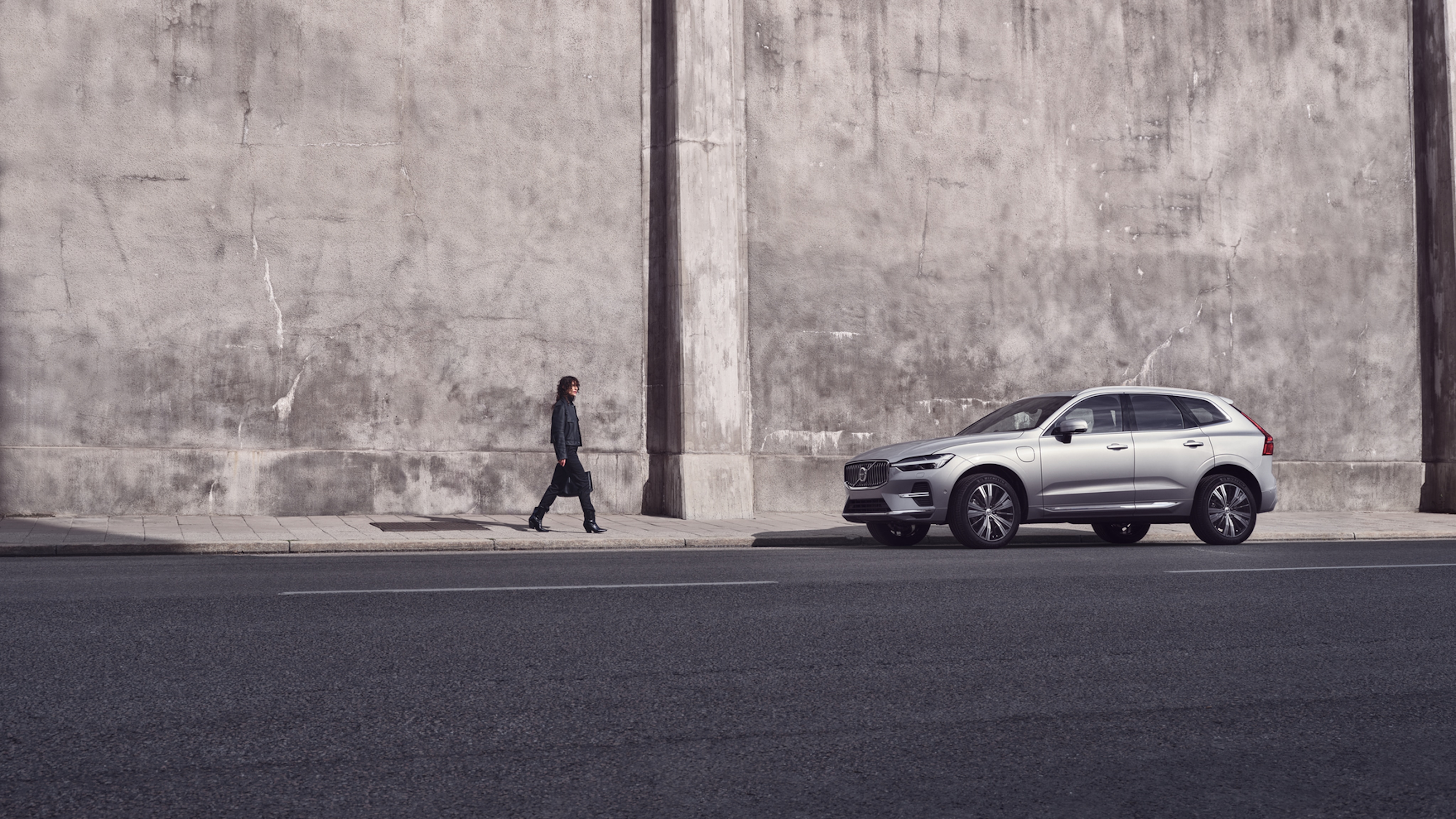 Person läuft auf einen Volvo XC60 Recharge zu - Seitschuss