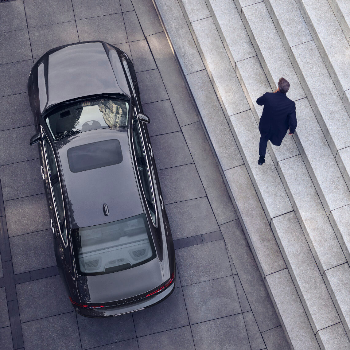 Mann geht neben Volvo S90 Recharge T8 Inscription Pebble Grey Metallic Stufen hoch