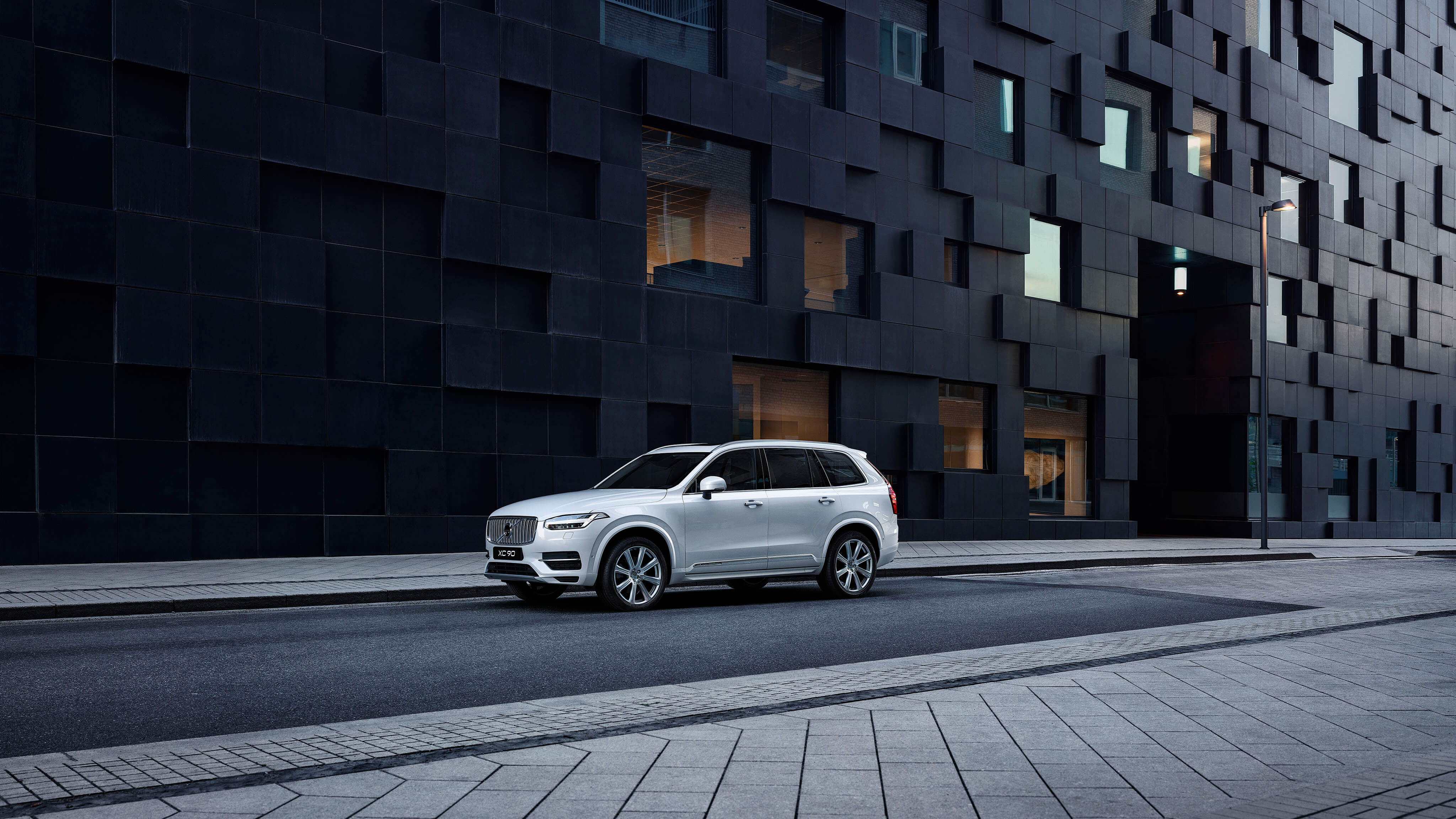 Volvo steht auf einer Straße neben einem schwarzen Gebäude - Frontseitenschuss