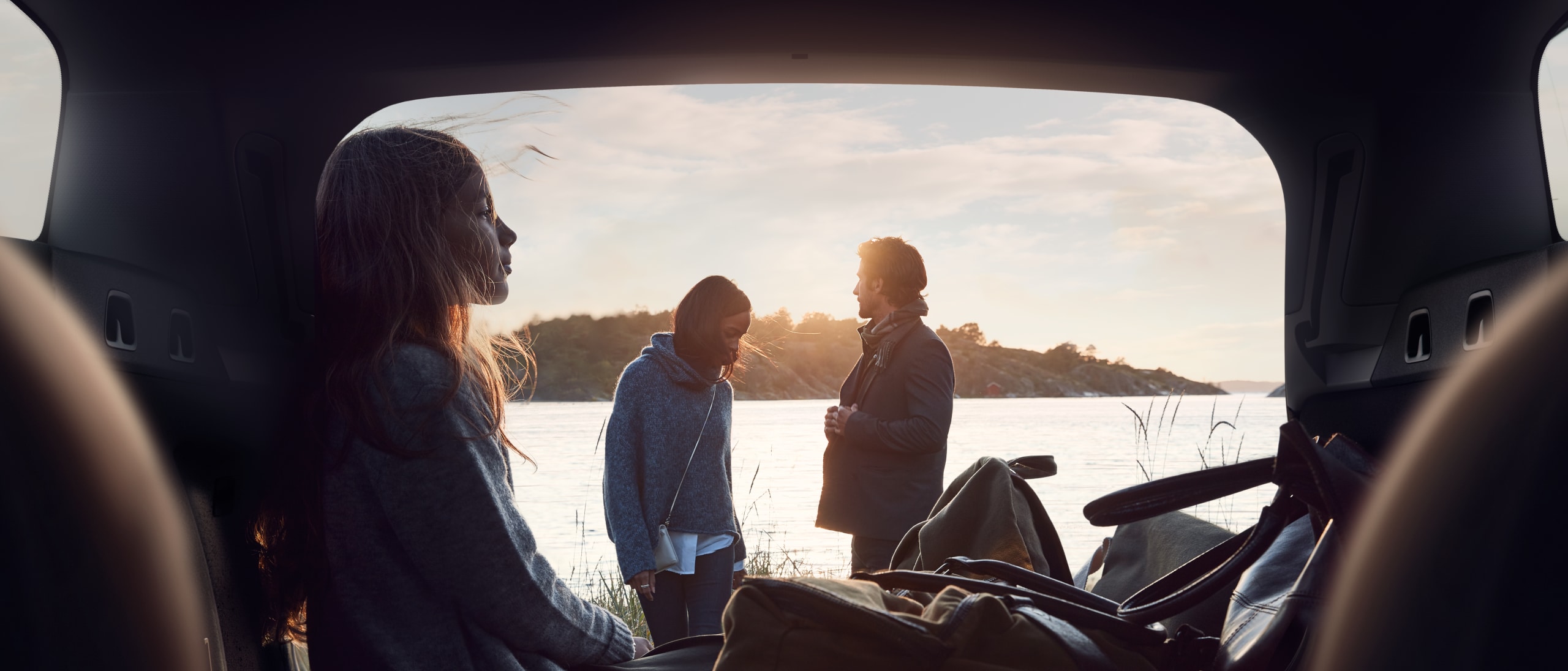 Blick aus dem Kofferraum eines Volvo - Familie am See