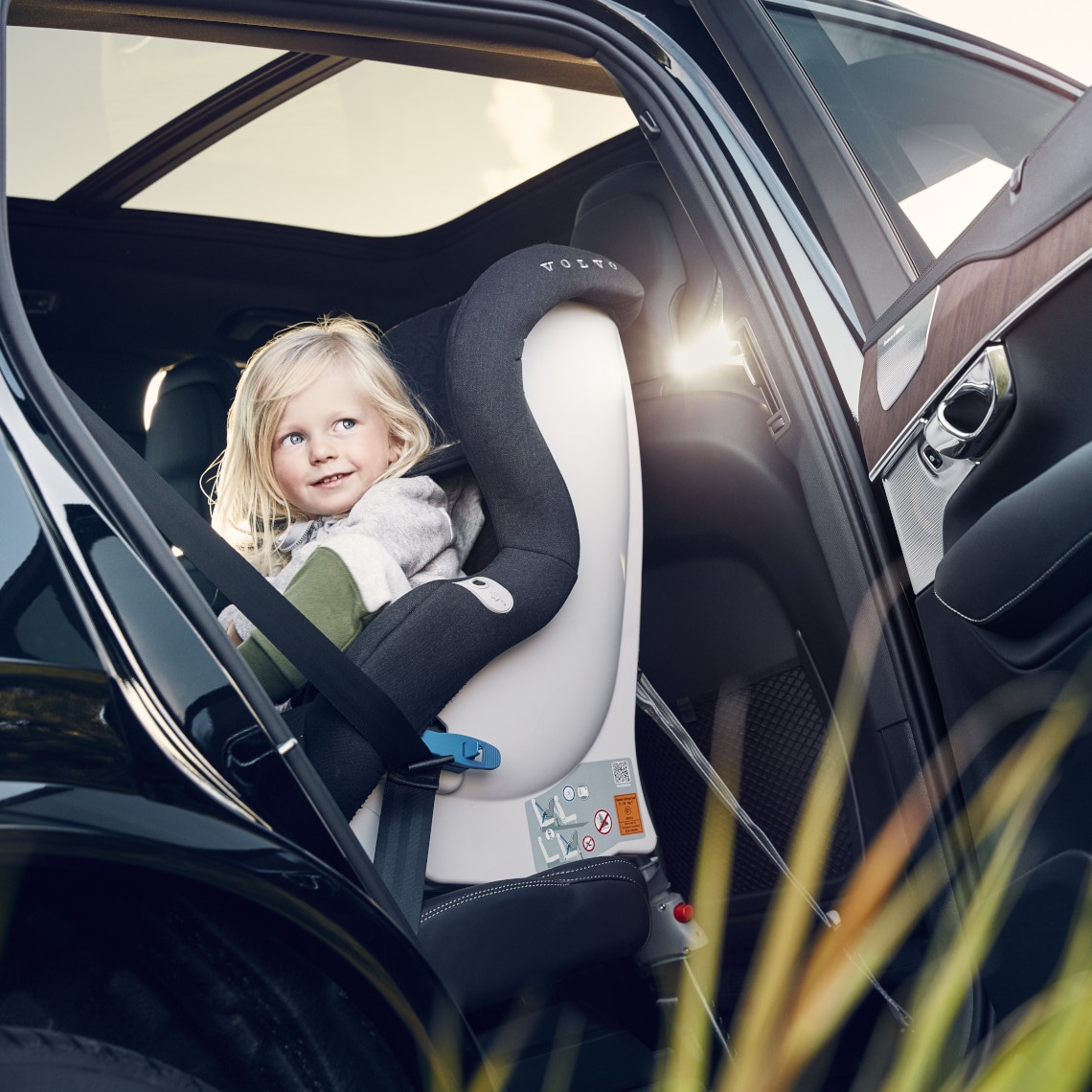 Kind sitzt im Kindersitz - Foto durch offenen Autotür