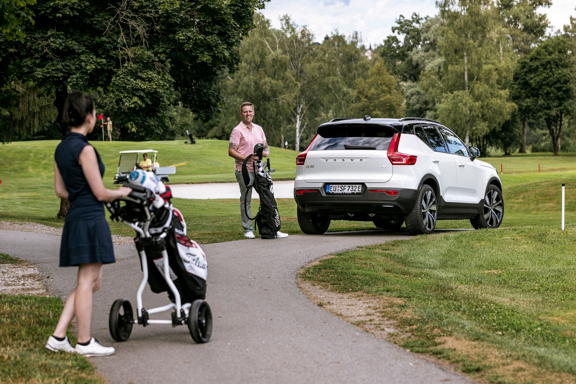Zwei Golfer:innen mit einem Volvo Fahrzeug auf dem Golfplatz. 