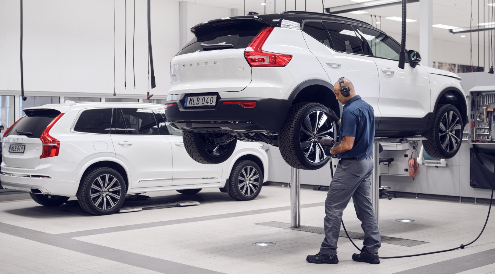 Volvo Mitarbeiter wechselt an einem Volvo-Fahrzeug, das auf einer Hebebühne steht, einen Reifen