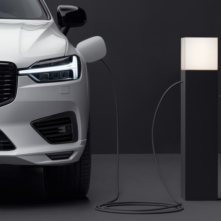 A white Volvo car from front, being charged via a charging station