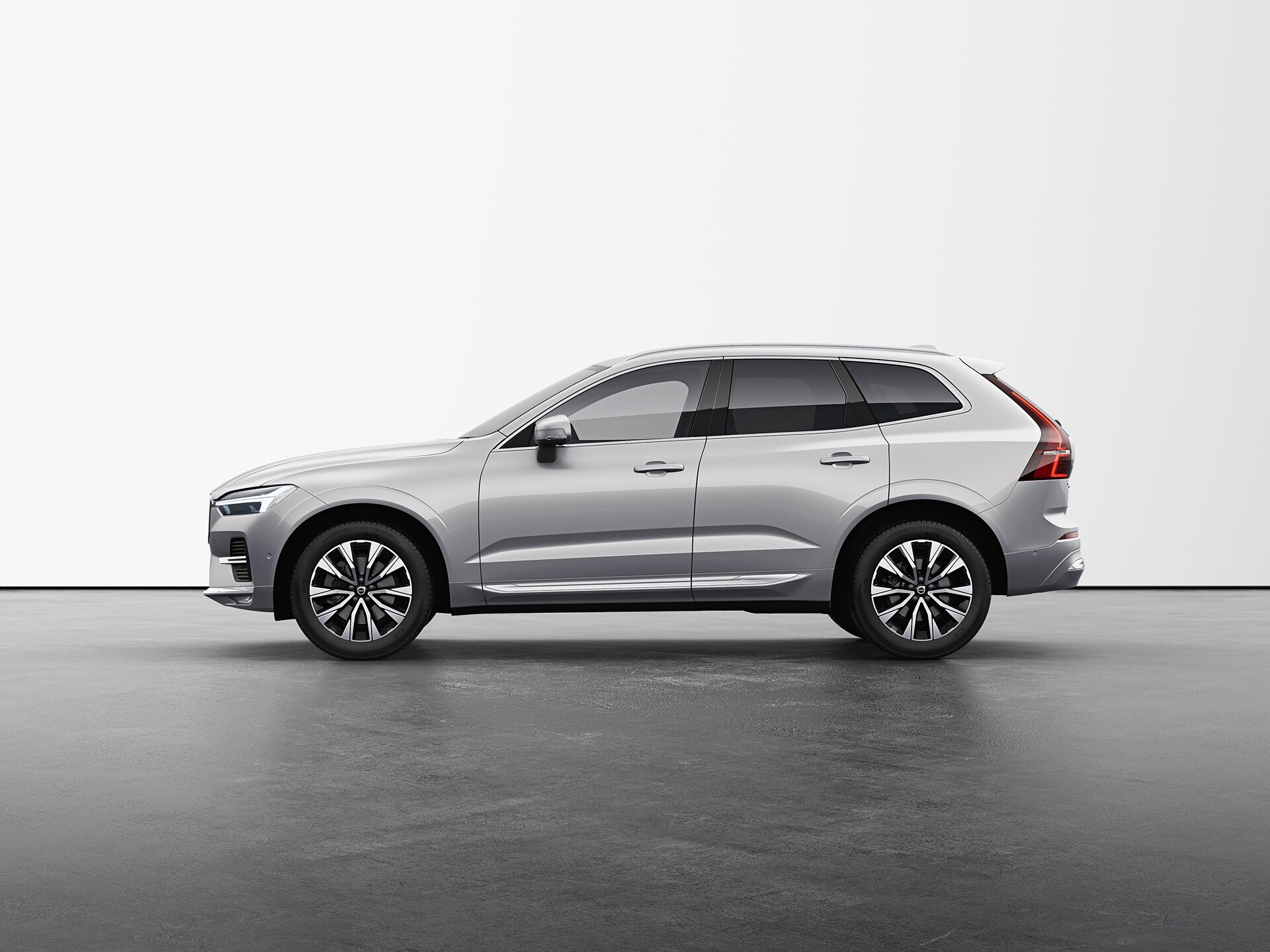 A silver Volvo XC60 compact SUV standing still on grey floor in a studio