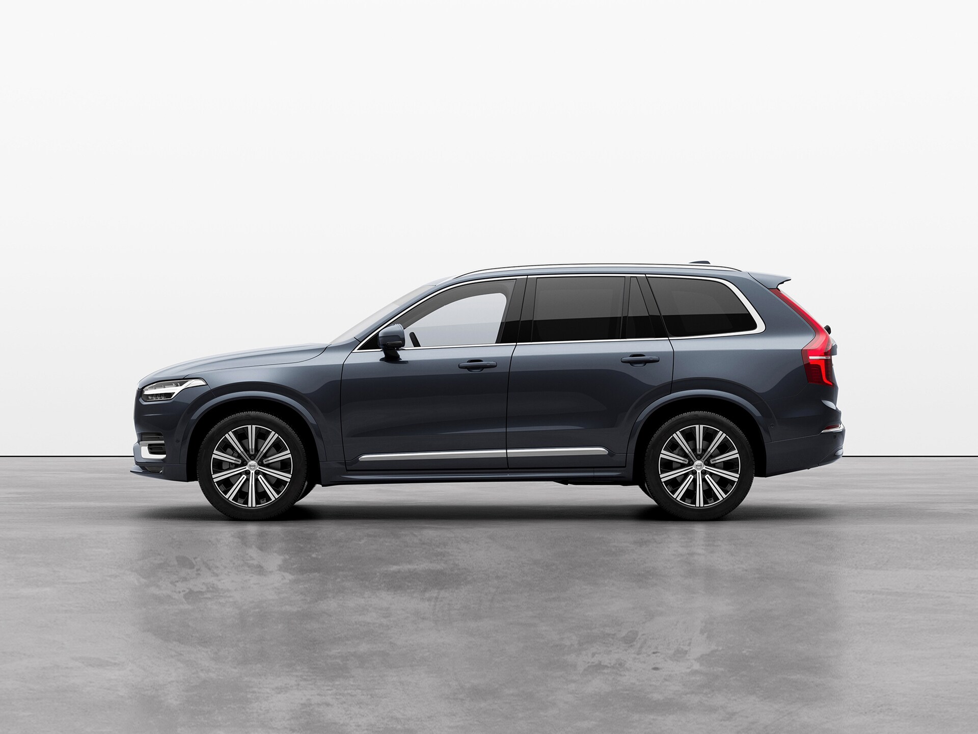 A silver Volvo XC90 compact SUV standing still on grey floor in a studio