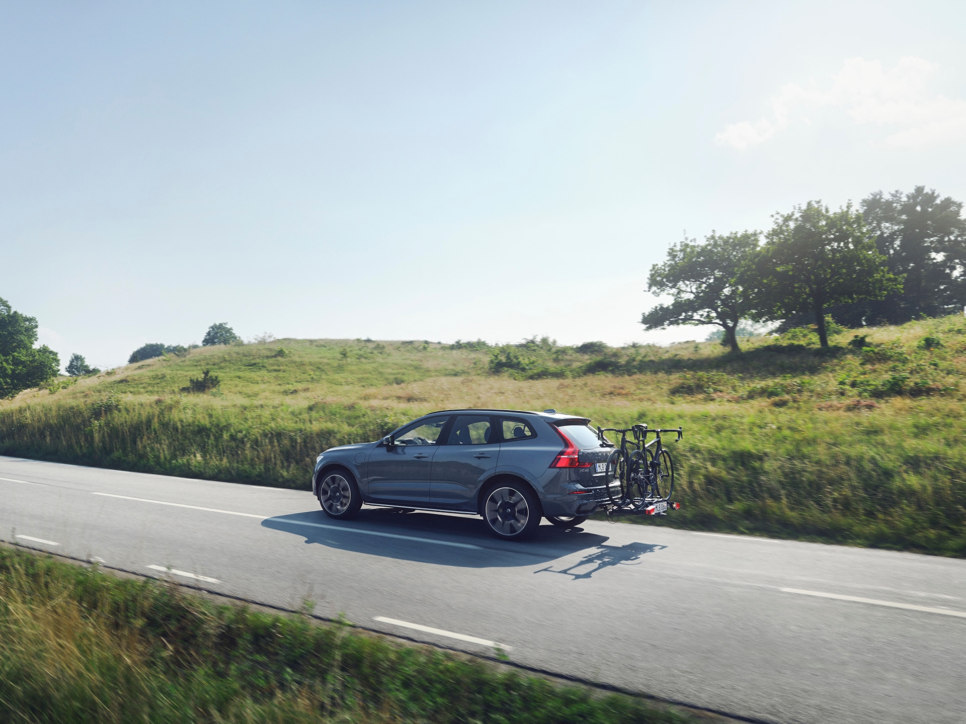 Un Volvo XC60 con portabicicletas conducido en una carretera que cruza una planicie de áreas verdes.