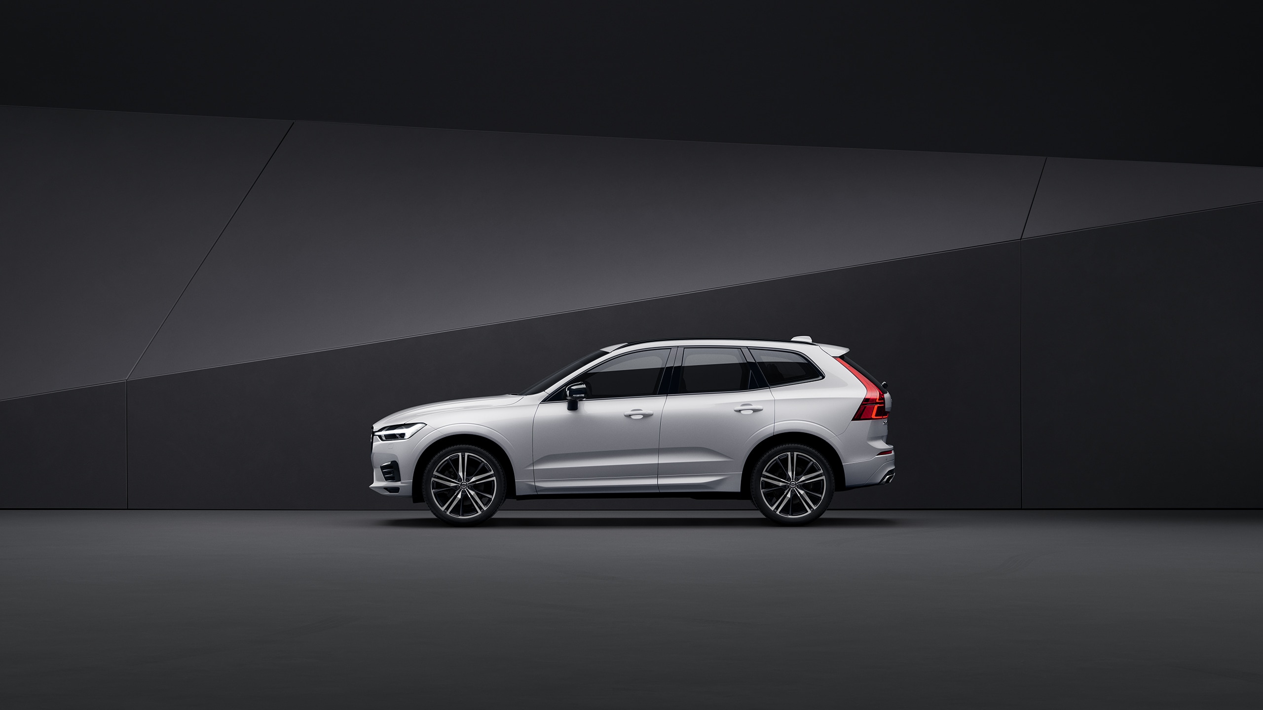 Side view of a silver Volvo XC60 parked in a black indoor environment.