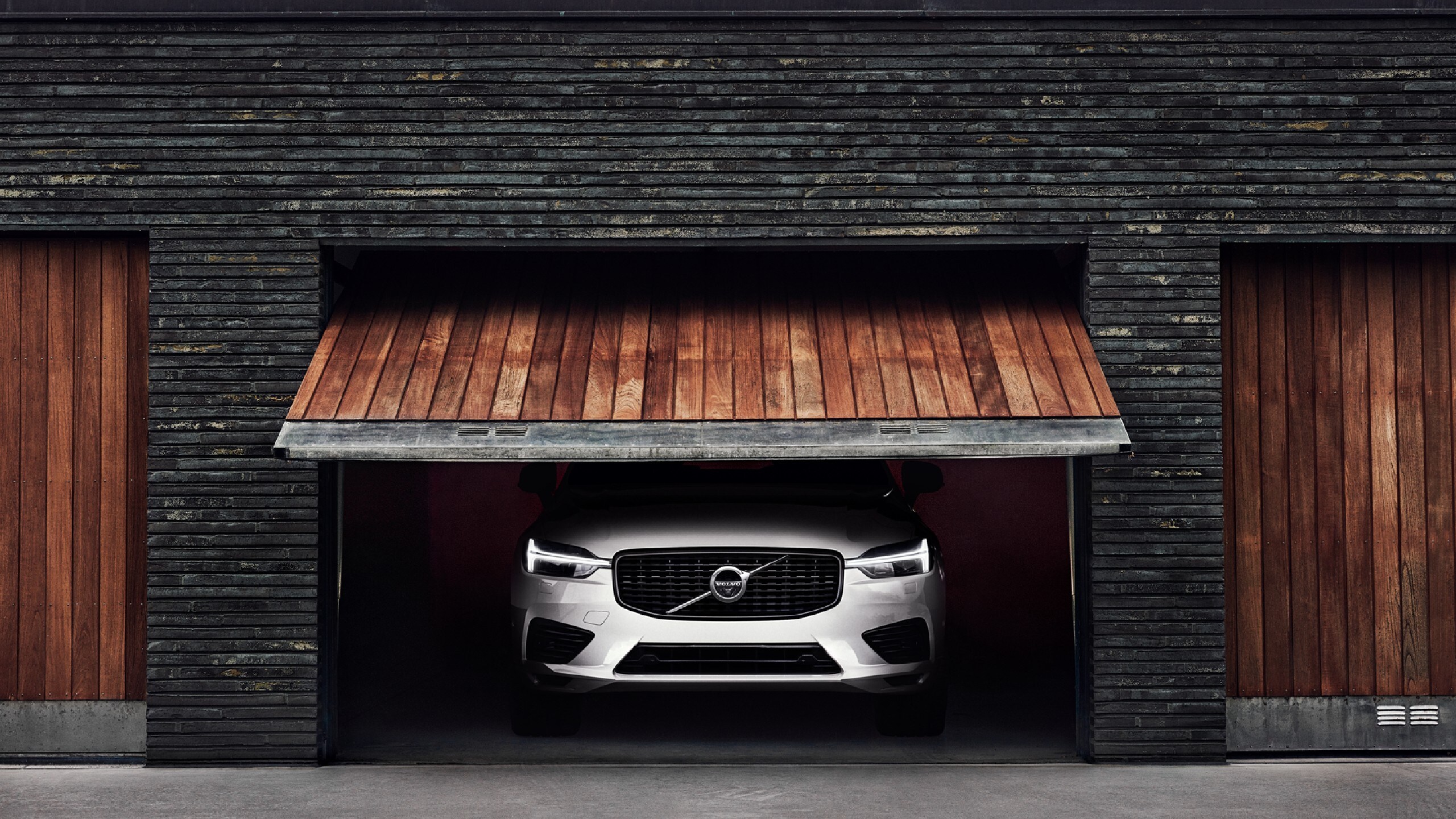 XC60 standing inside a garage, while the wooded front gate is opening.