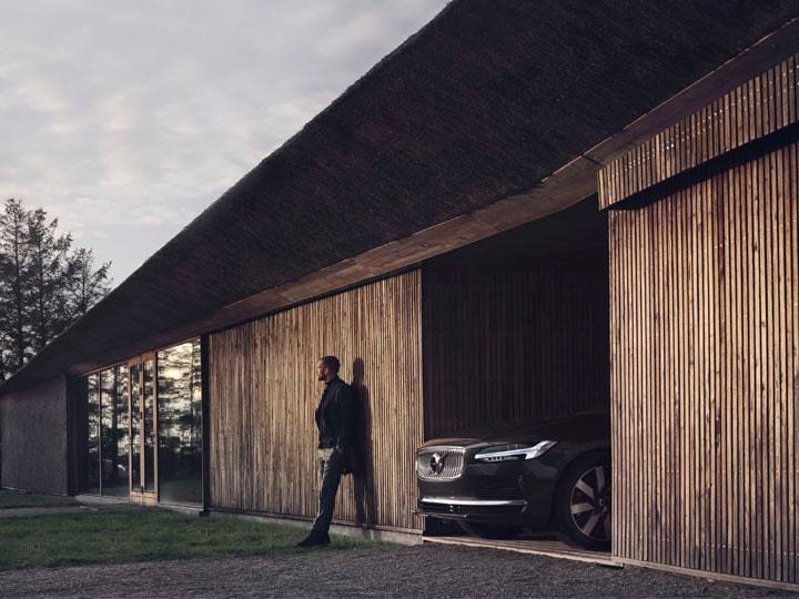 Un hombre de pie y un Volvo saliendo de un garaje de una casa