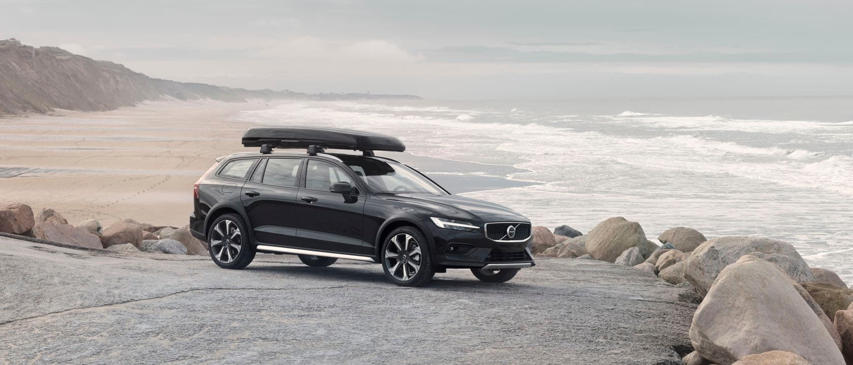 Volvo V60 Cross Country con un cofre de techo junto a una playa