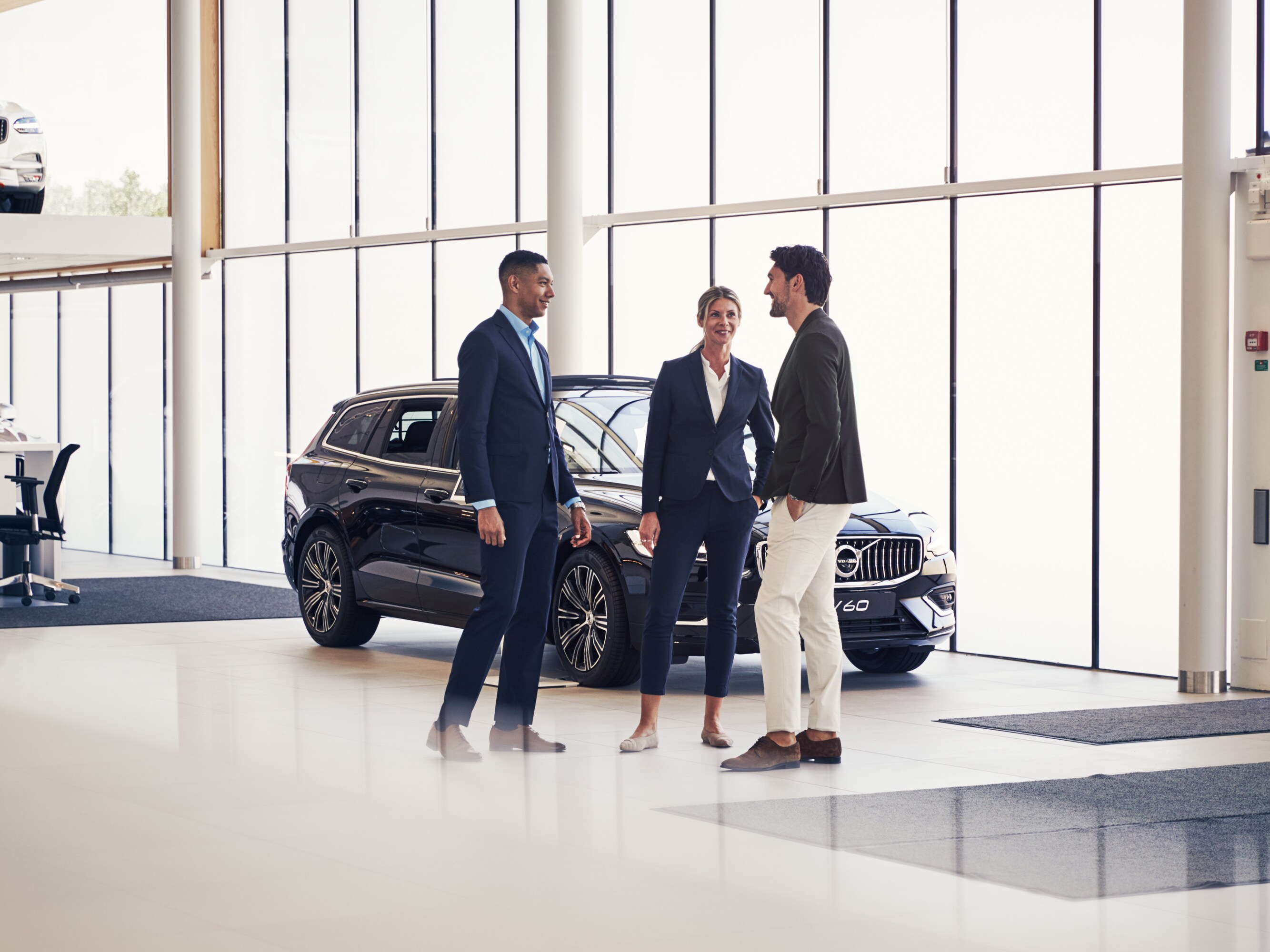 Tre personer i samtal framför en Volvo V60.