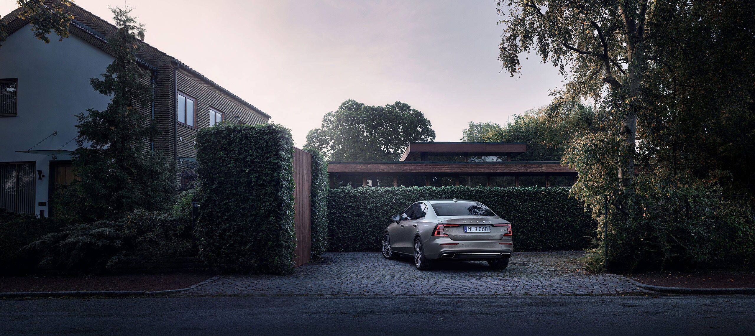 Grå Volvo S60 parkerad vid villa