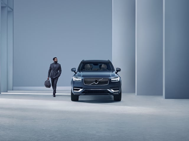 En man som står bredvid en blå Volvo XC90