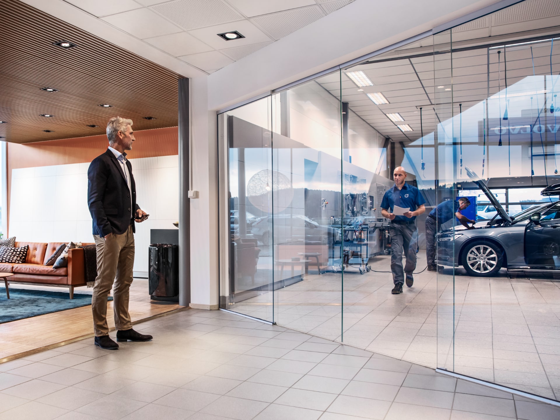 Un homme se tient dans la salle d'attente de l'atelier Volvo.