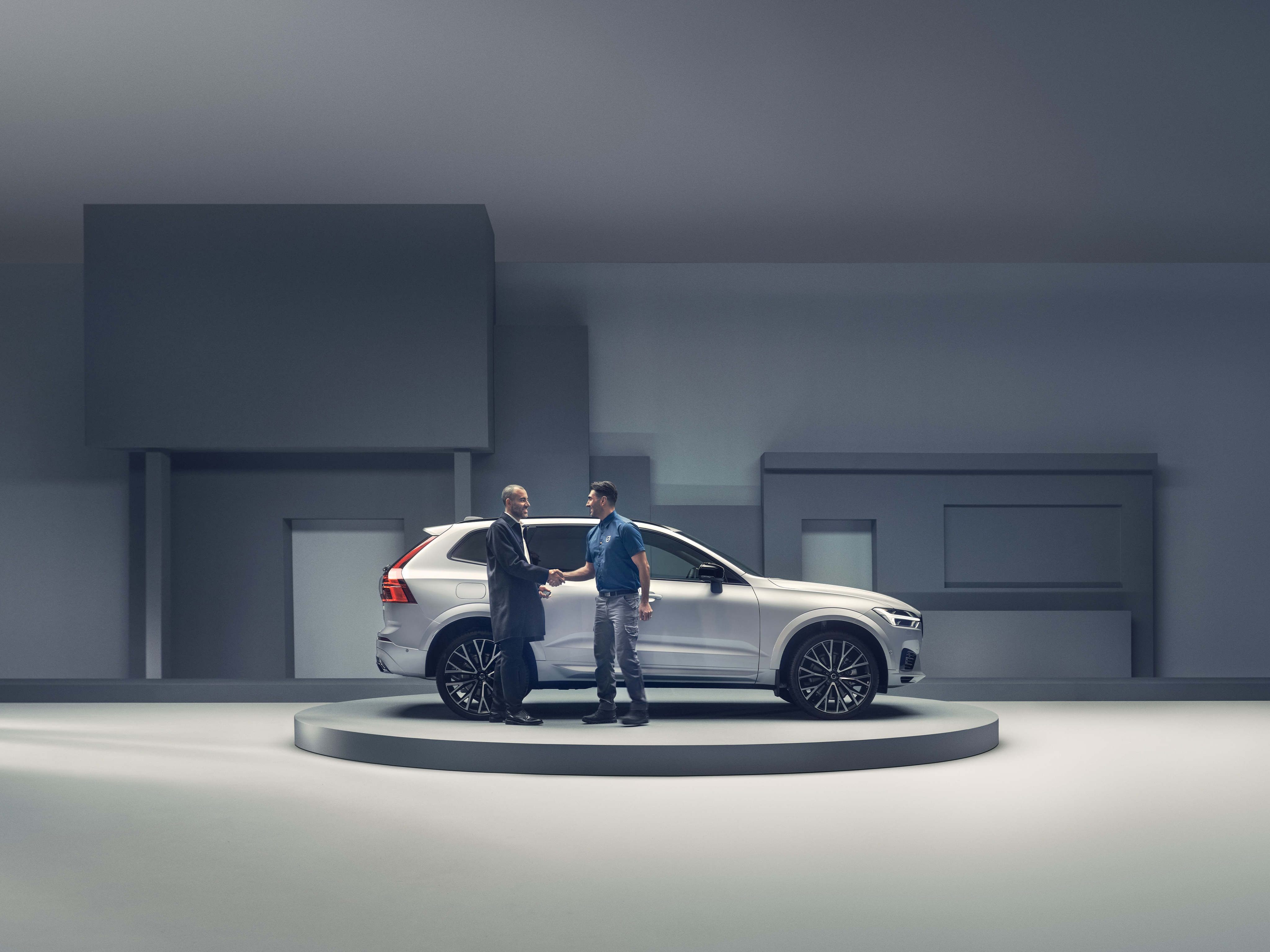 Zwei Menschen stehen in einem Showroom vor einem weißen Volvo