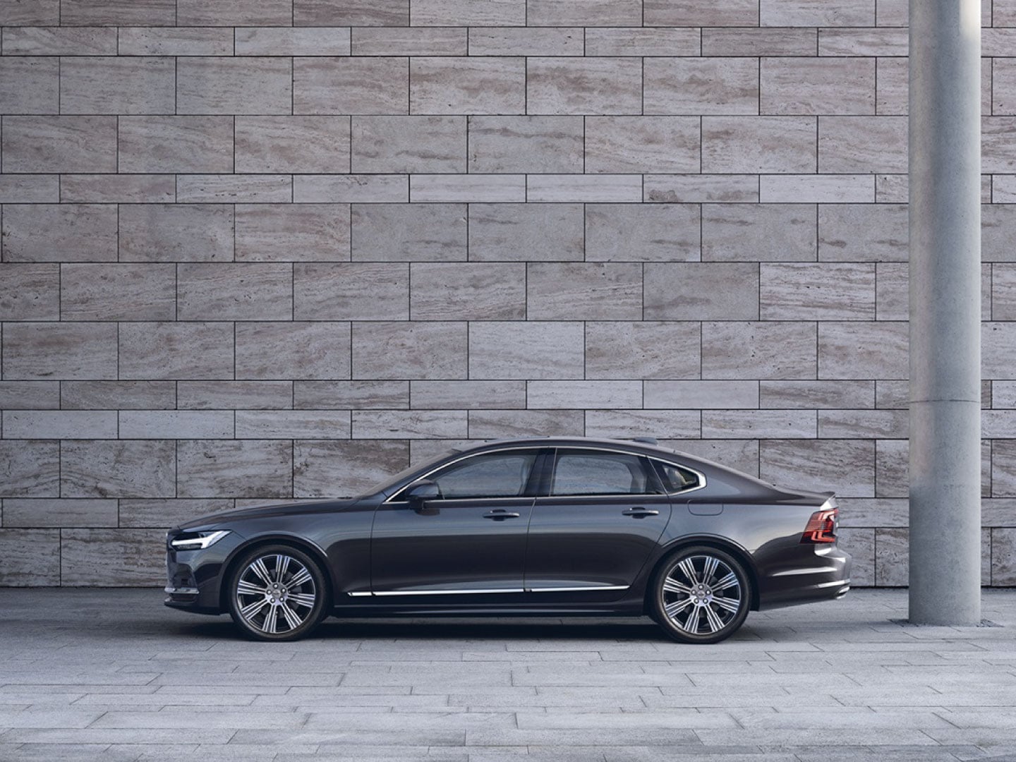停在灰色水泥牆前的 Volvo S90 側視圖。