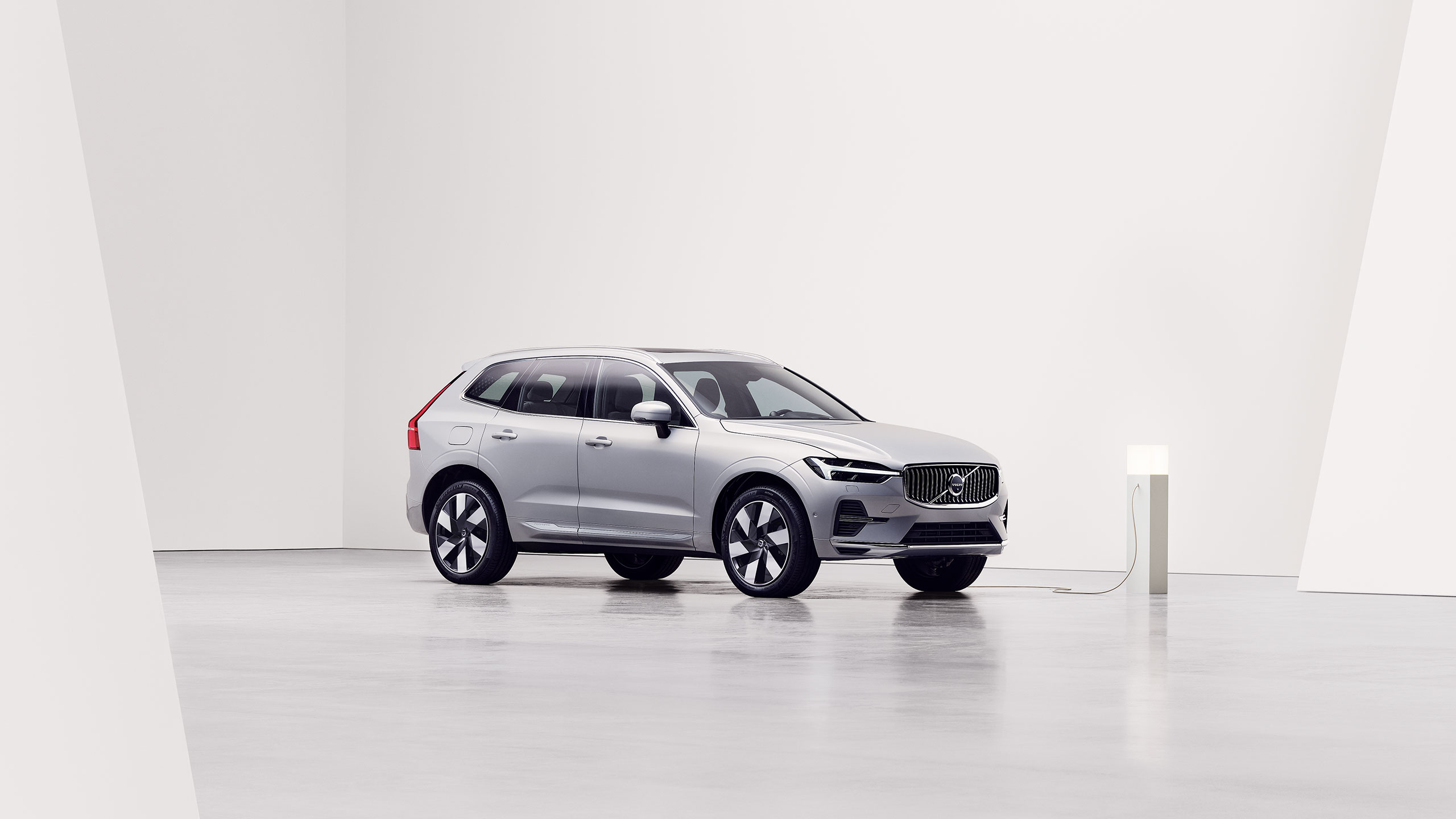 Side view of silver Volvo XC60 Recharge being charged at charging station
